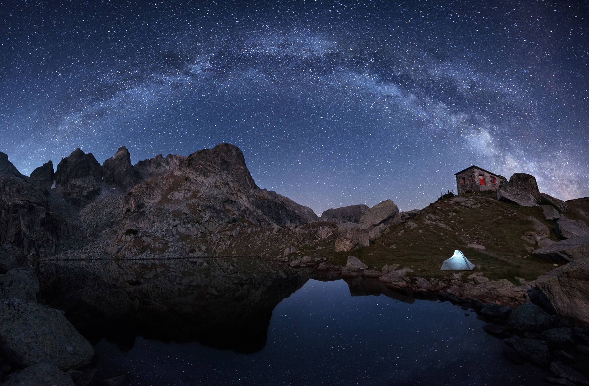 Tent and cabin under the Milky Way by a mountain lake HD Wallpaper