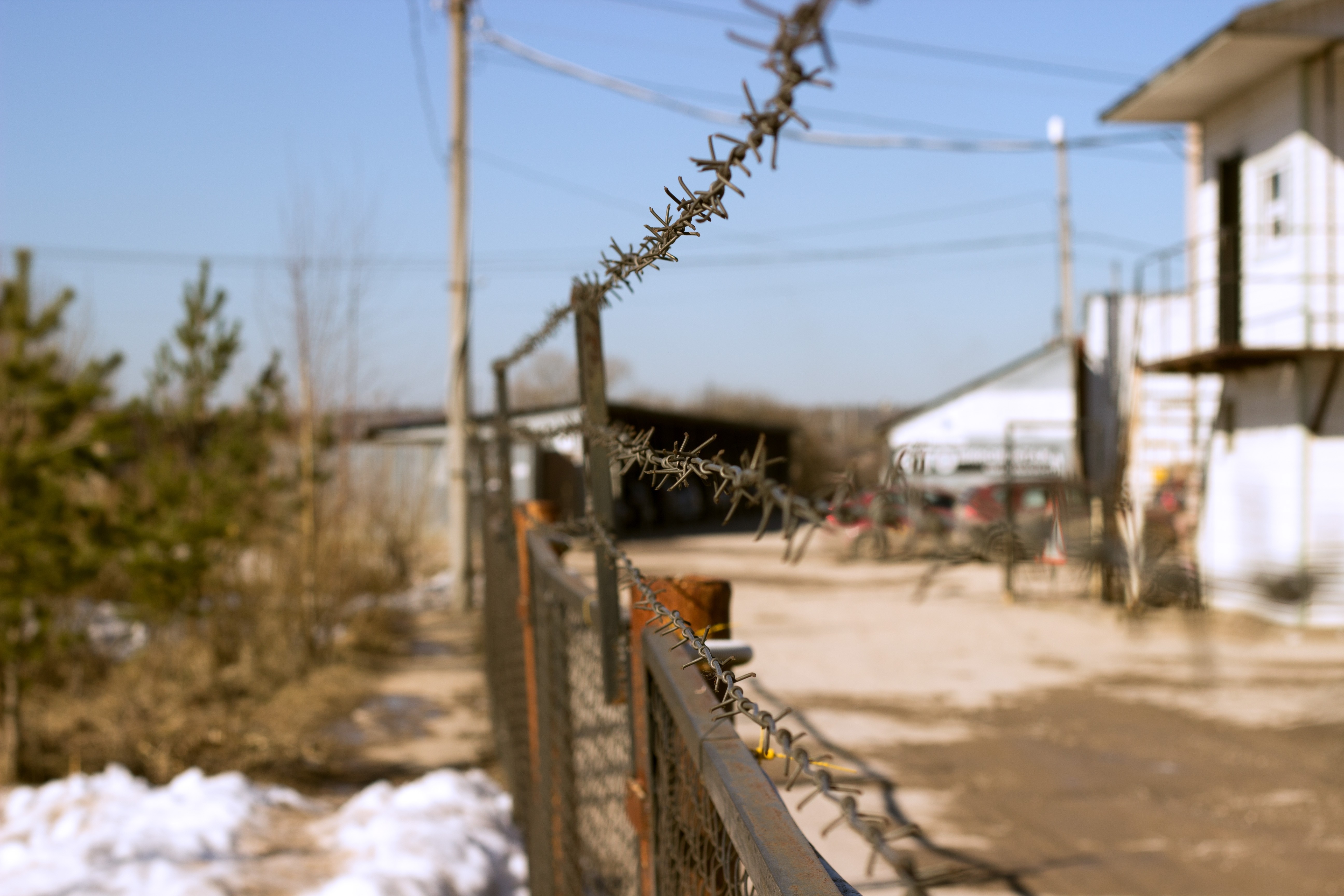 Barbed wire fence in front of industrial buildings HD Wallpaper