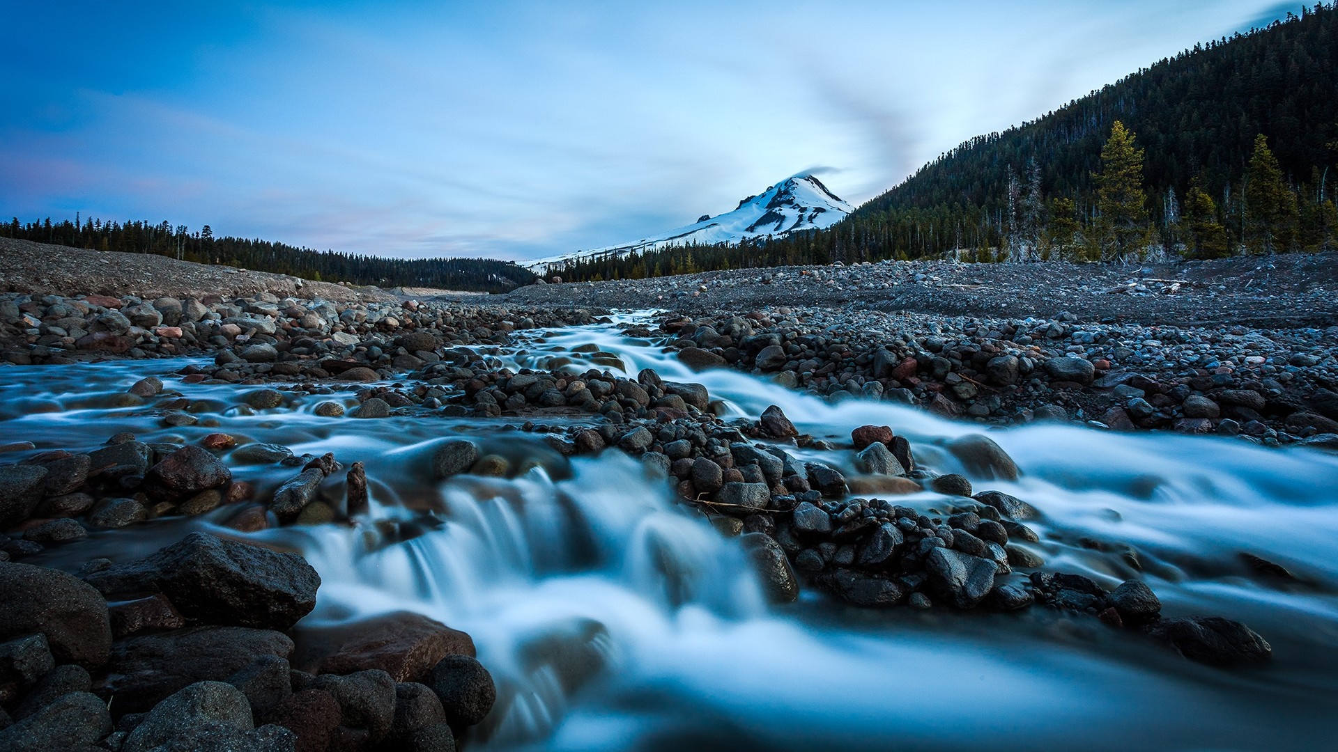River flowing through rocky valley towards snow-capped mountain HD Wallpaper