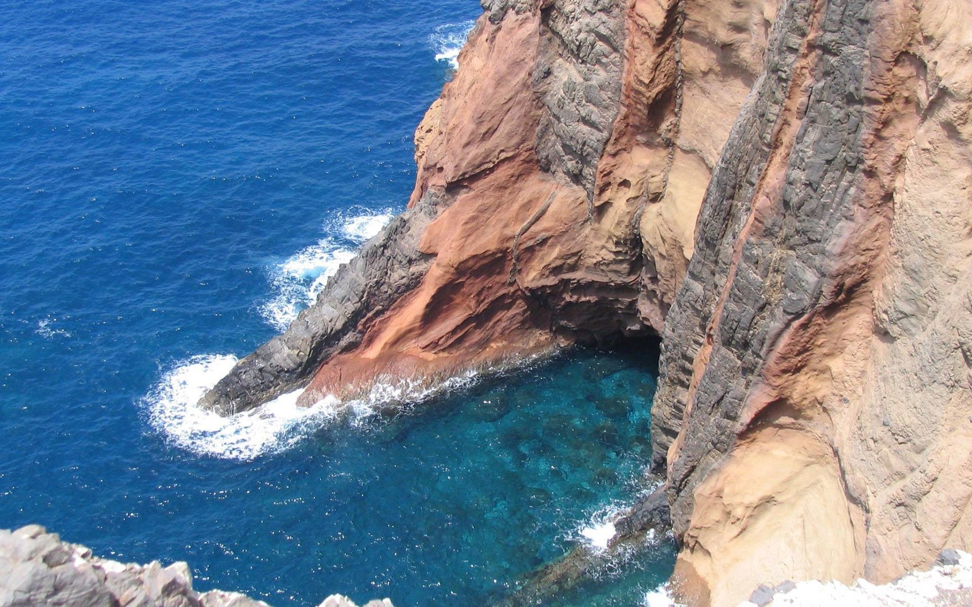 Ocean waves crashing against a rocky cliff formation HD Wallpaper