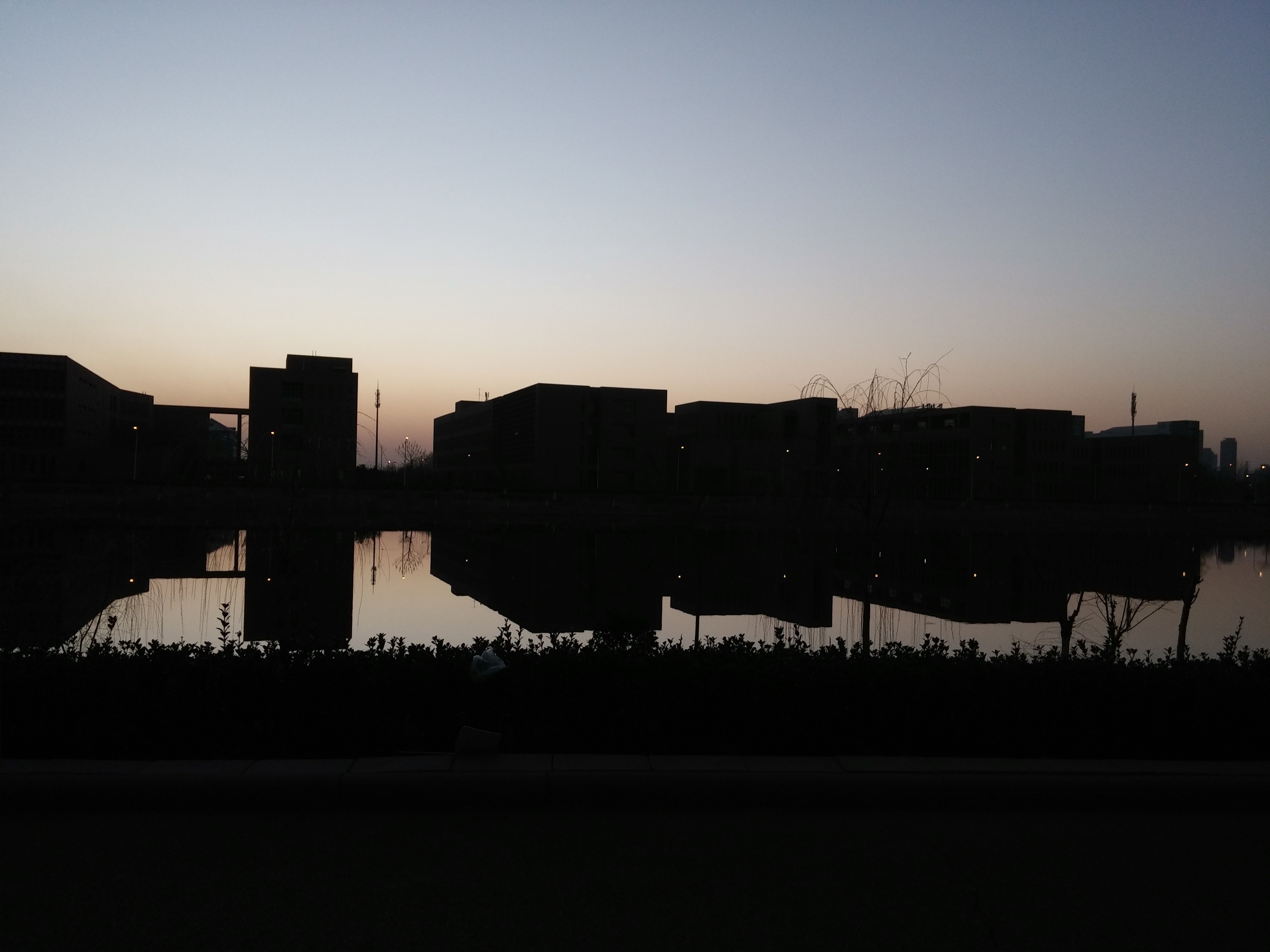 Silhouette of buildings reflected in water at dusk HD Wallpaper
