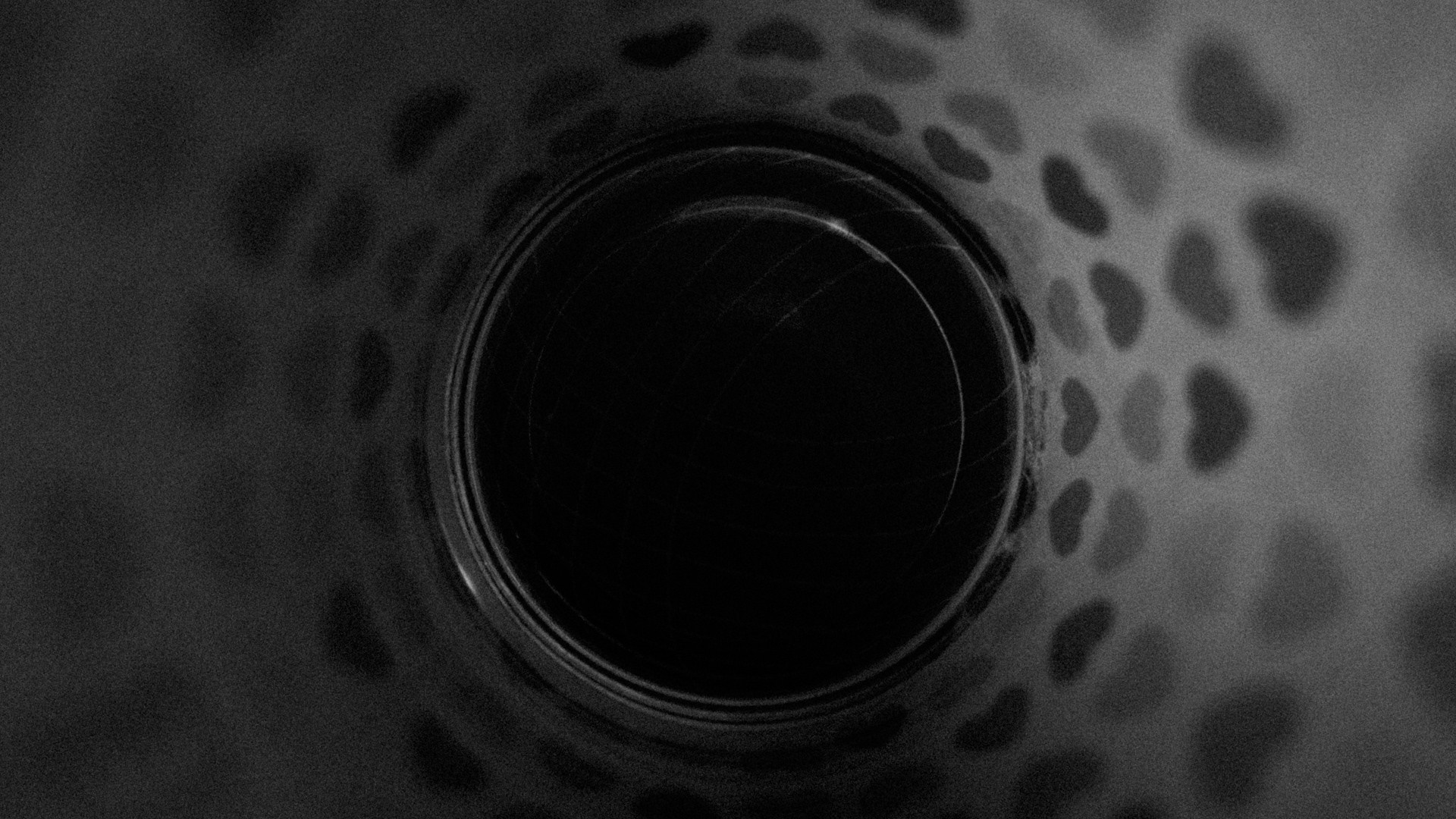 Monochrome close-up of a dark circular opening with heart-shaped patterns HD Wallpaper