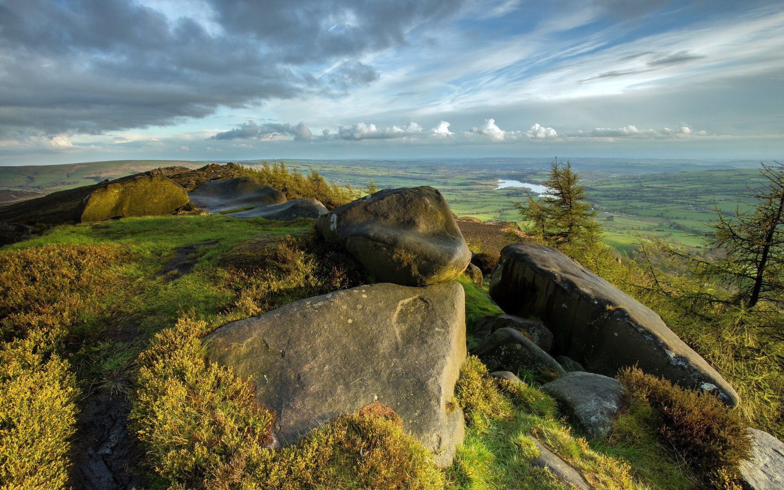 Rocky outcrop overlooking a valley with a lake HD Wallpaper