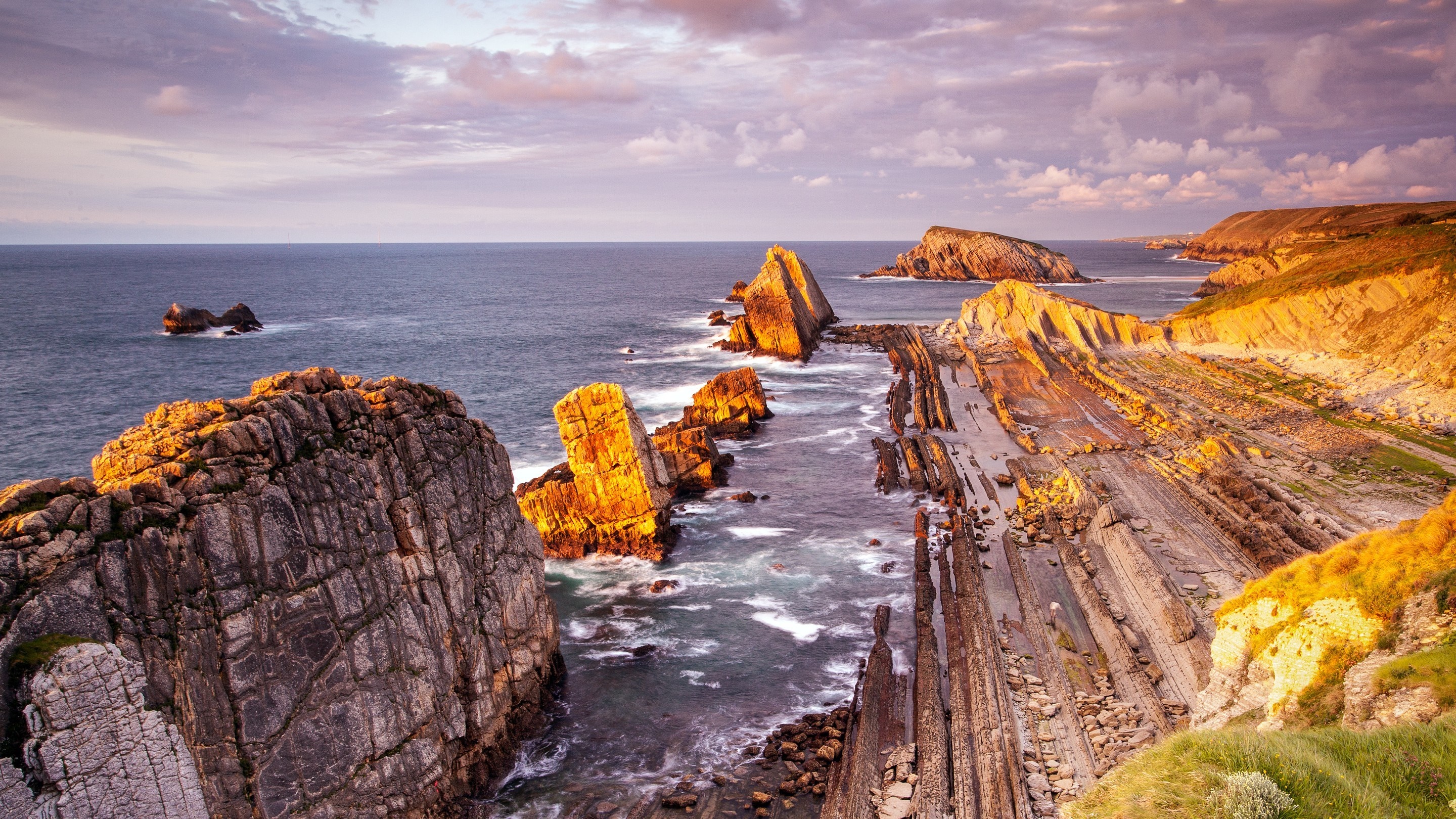Rocky coast at sunset with waves crashing HD Wallpaper