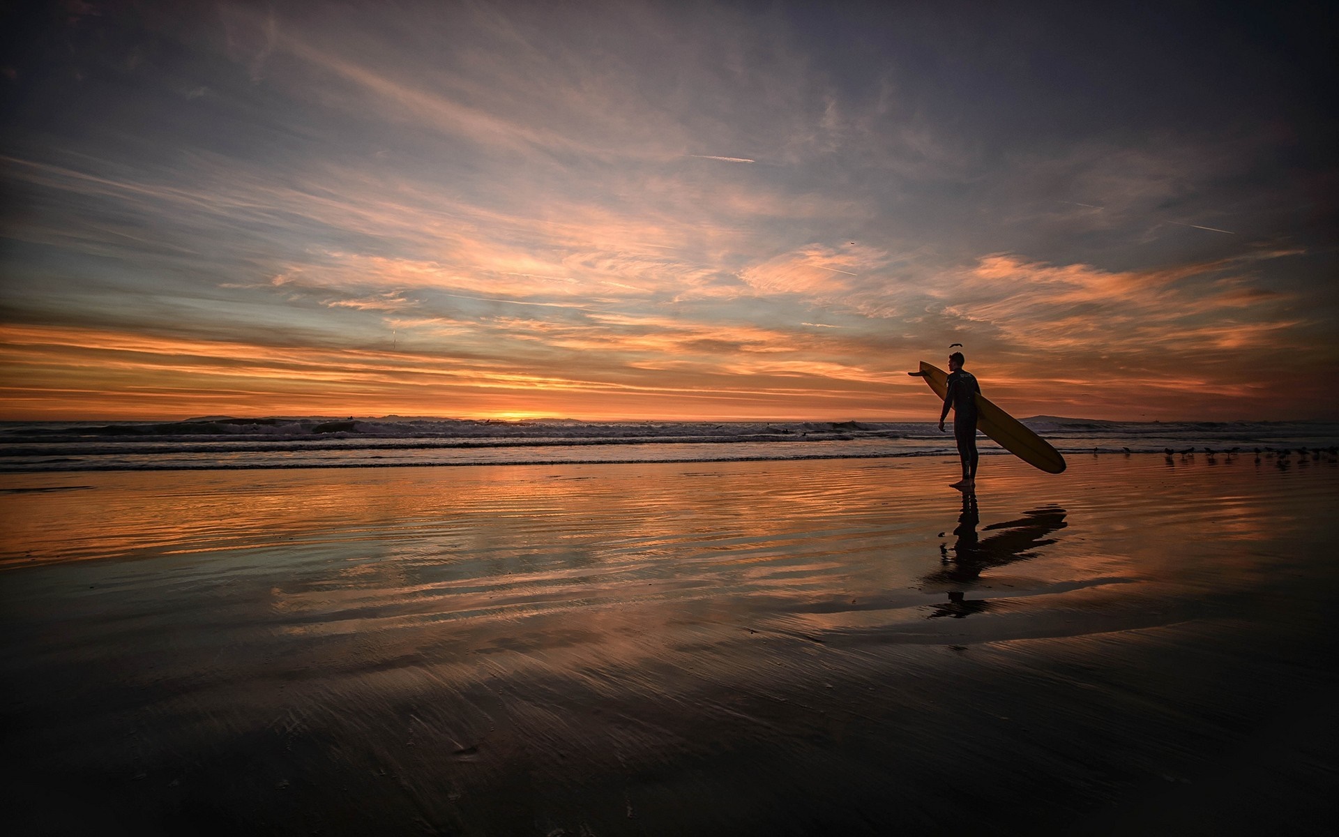 Surfer with surfboard on beach at sunset HD Wallpaper