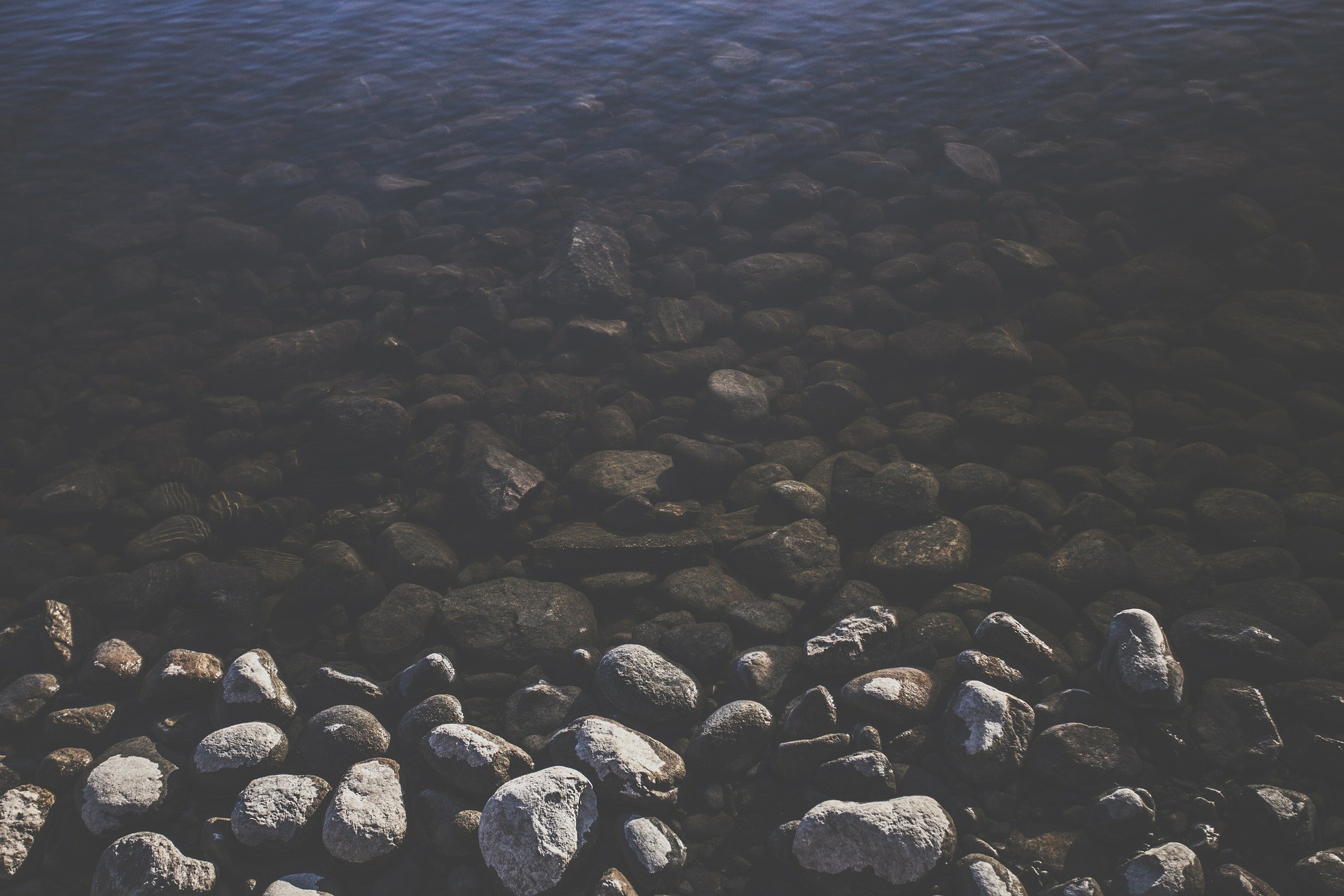 Rocks submerged in dark water HD Wallpaper