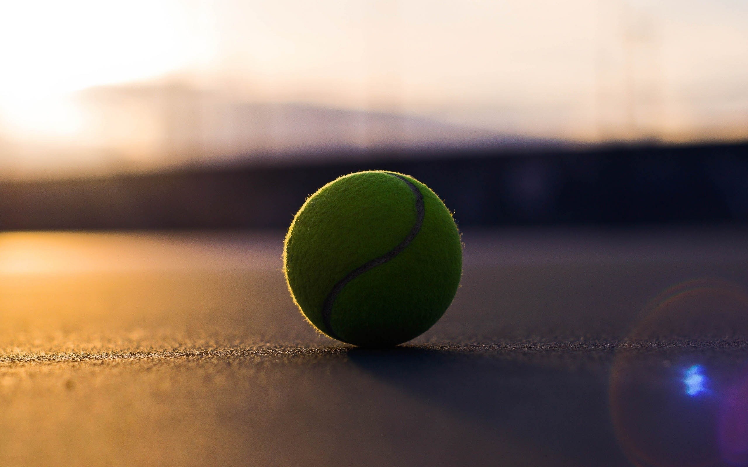 Tennis ball on a court at sunset with lens flare HD Wallpaper
