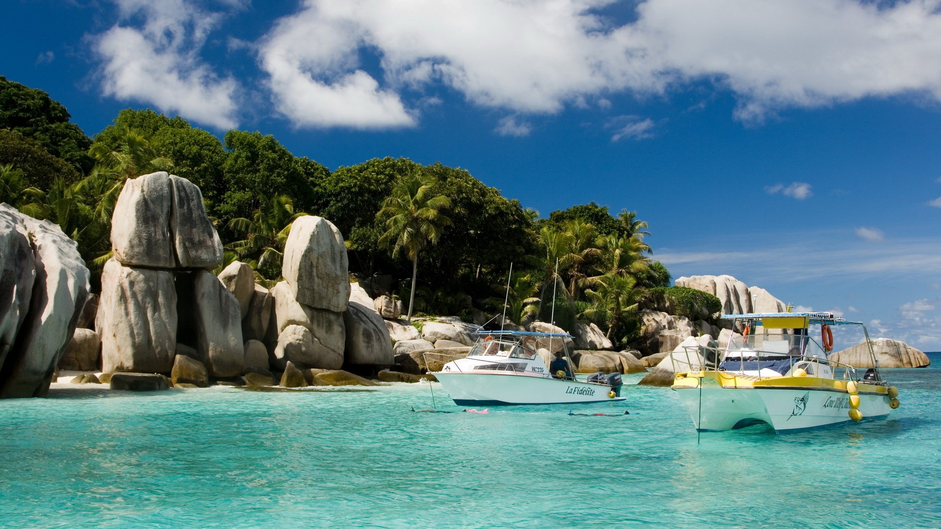 Boats near granite boulders and tropical island HD Wallpaper