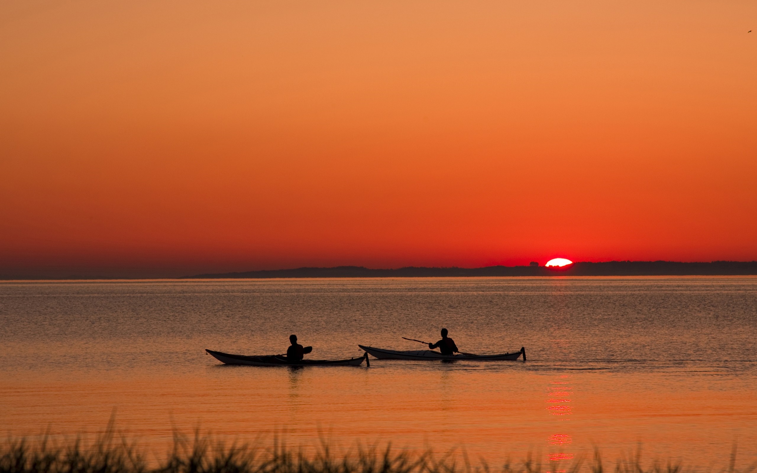 Two kayakers paddle on the sea at sunset HD Wallpaper