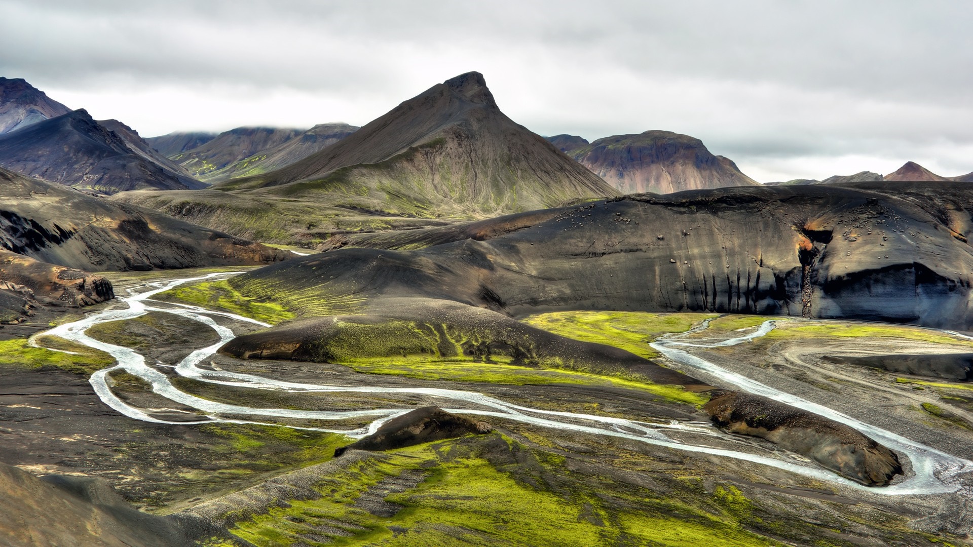River flowing through a volcanic landscape with mountains HD Wallpaper