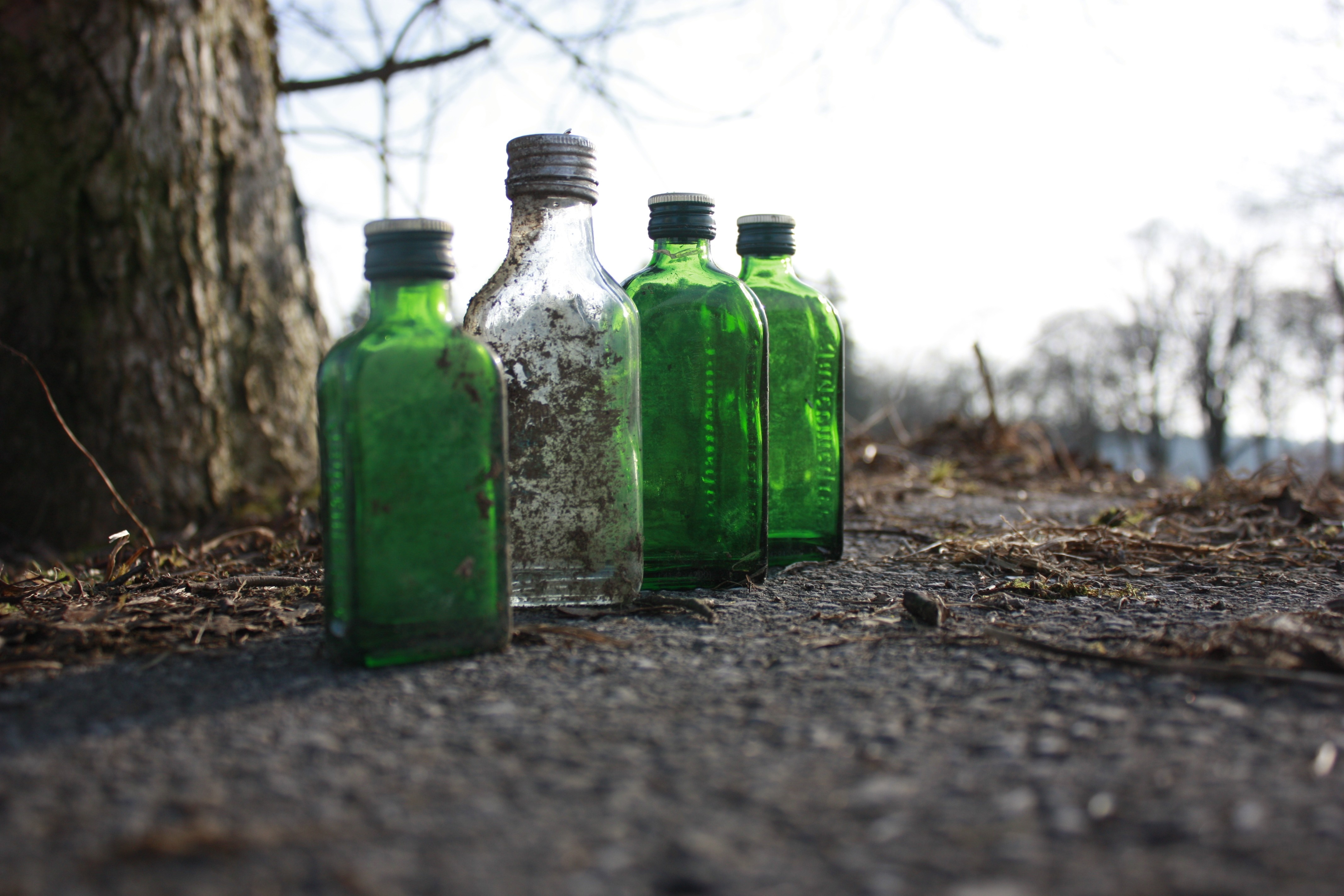 Four green bottles and one dirty bottle on the ground HD Wallpaper