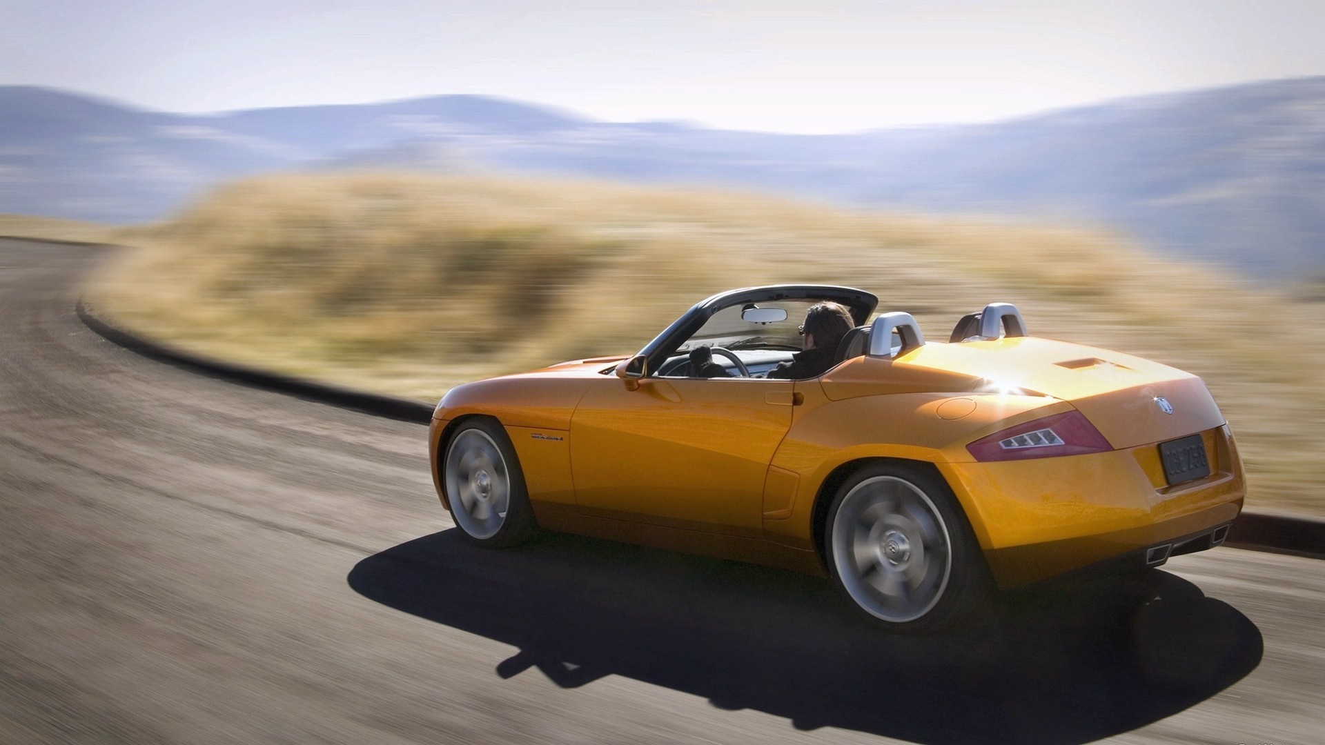 Orange convertible sports car driving on a winding road HD Wallpaper