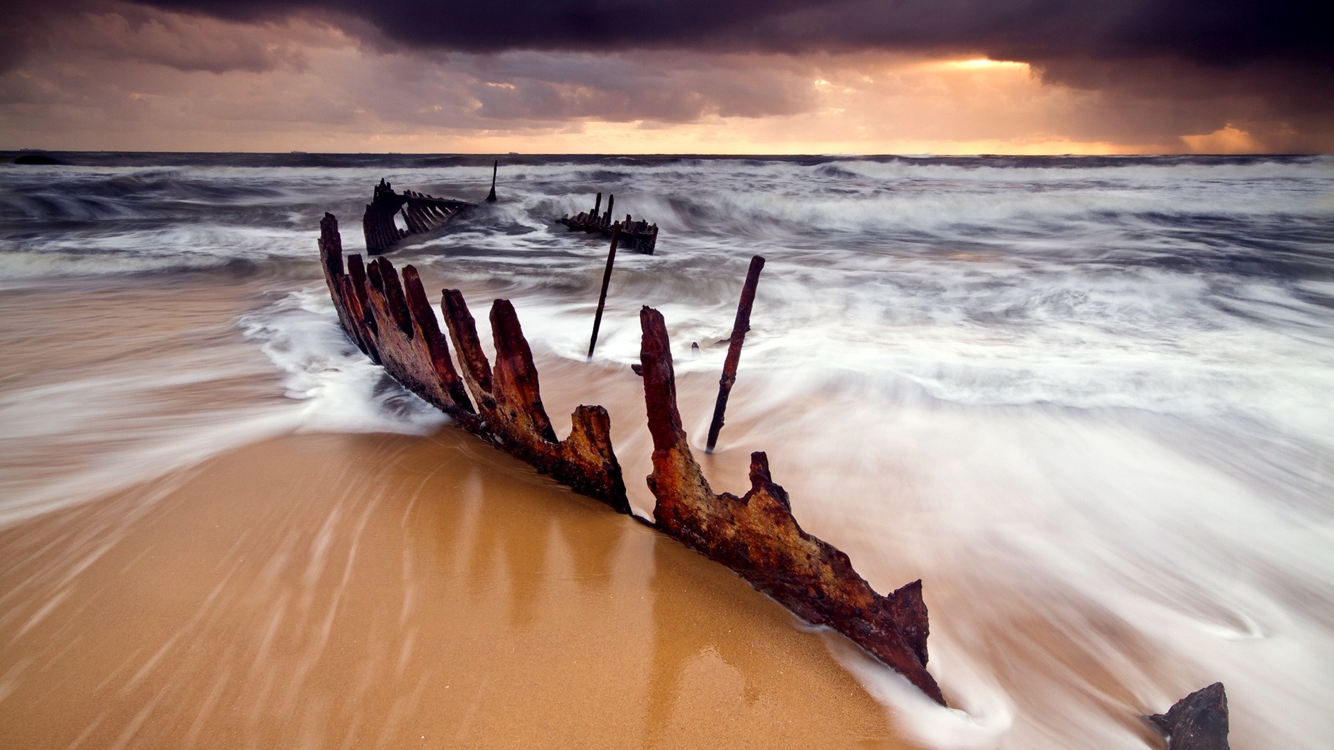 Shipwreck on a beach during sunset with waves HD Wallpaper