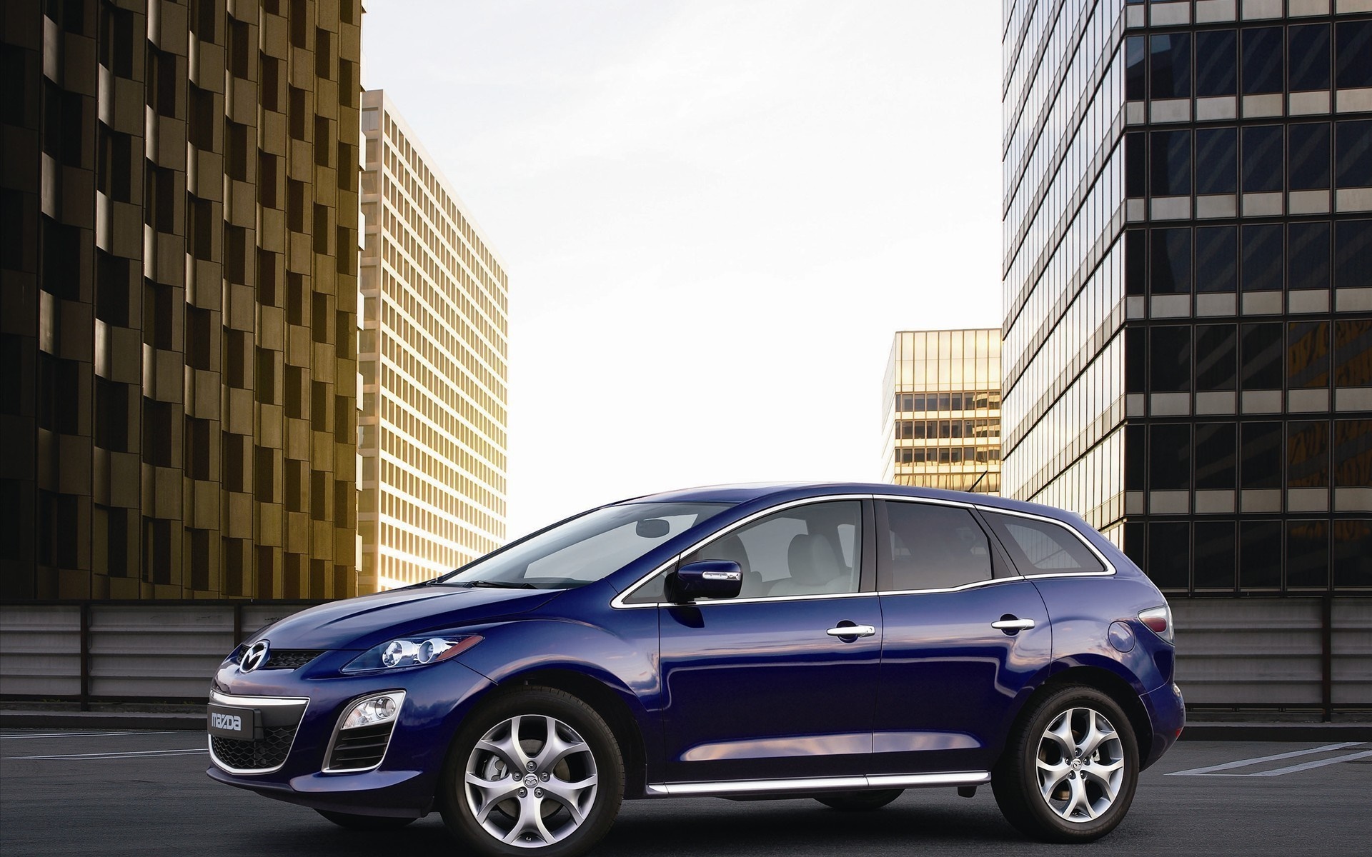 Blue Mazda CX-7 parked in front of modern buildings HD Wallpaper