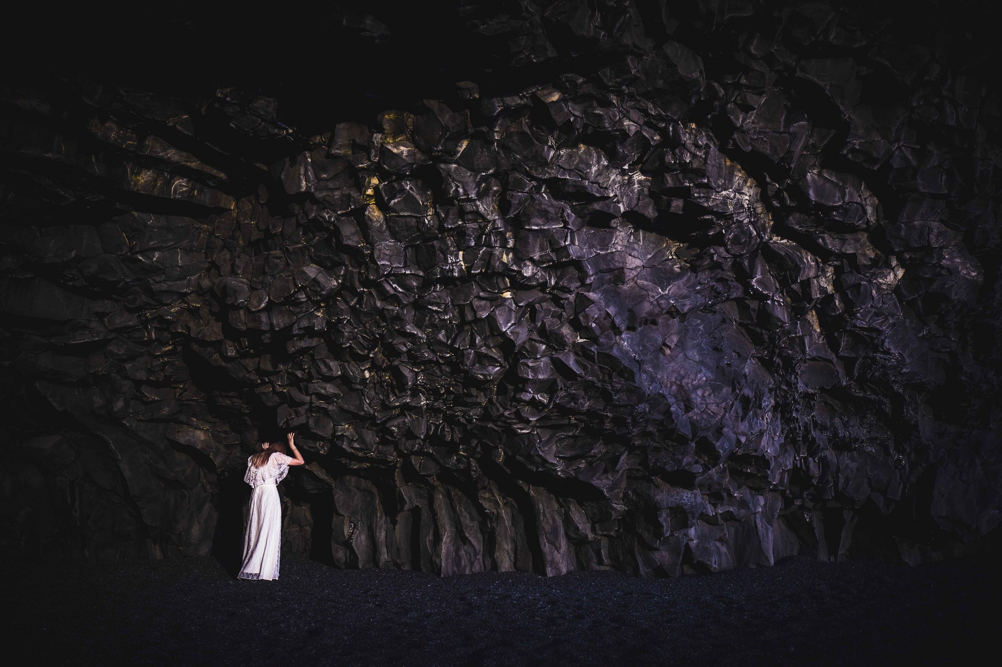 Woman in white dress in a dark cave with rock formations HD Wallpaper