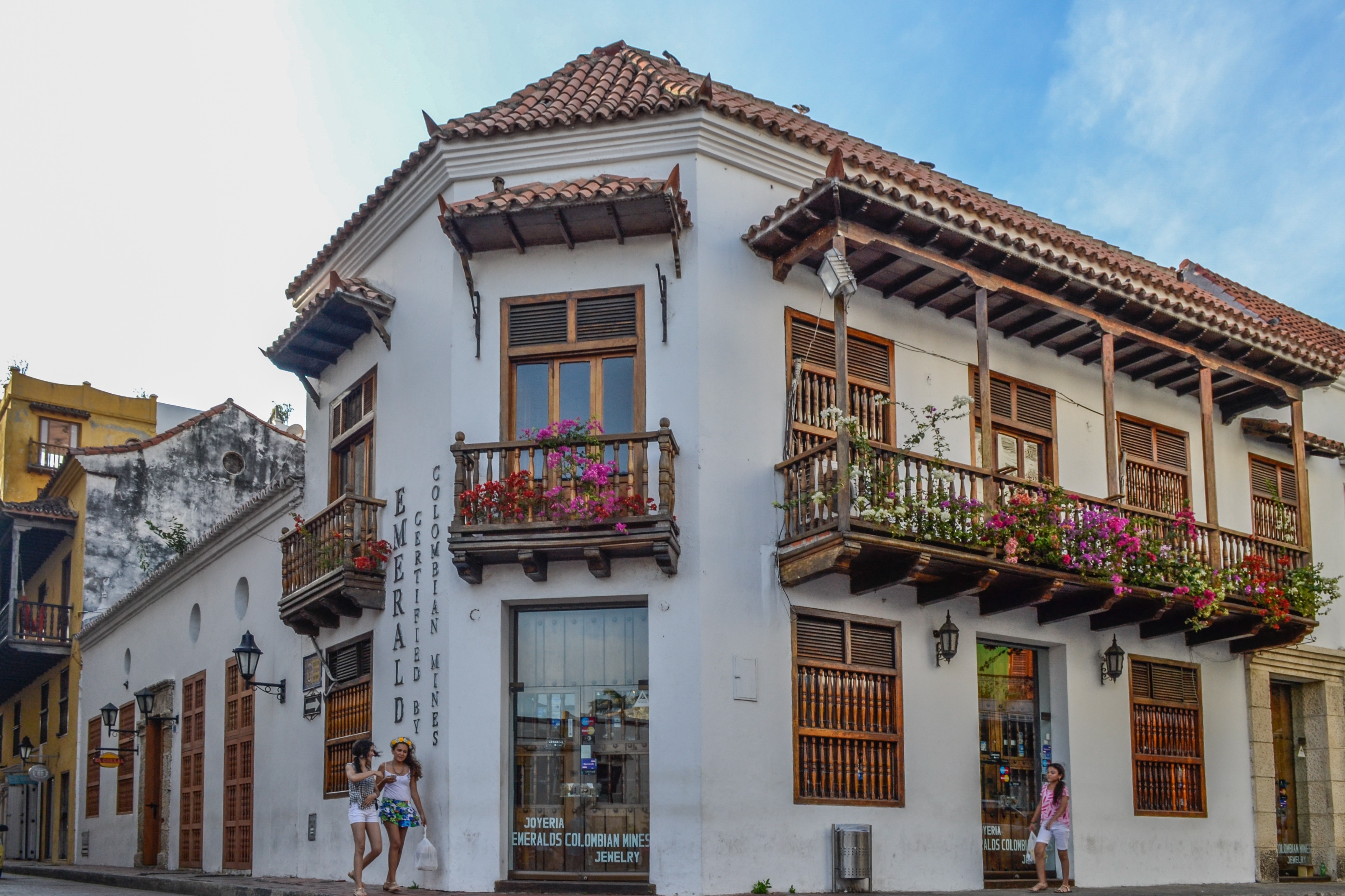 Corner building with balconies and shops in a town HD Wallpaper