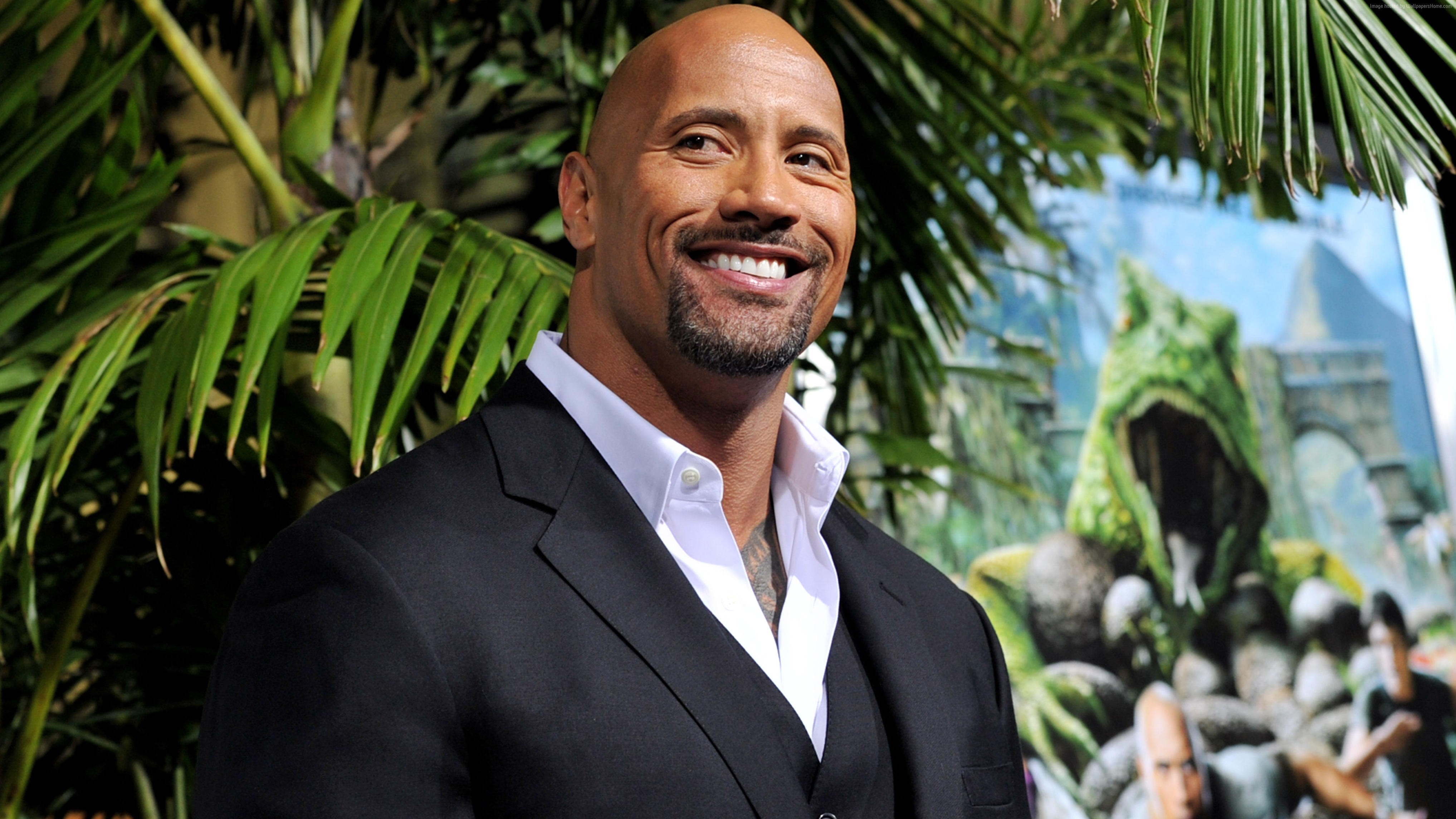 Dwayne Johnson in a suit with a jungle backdrop HD Wallpaper