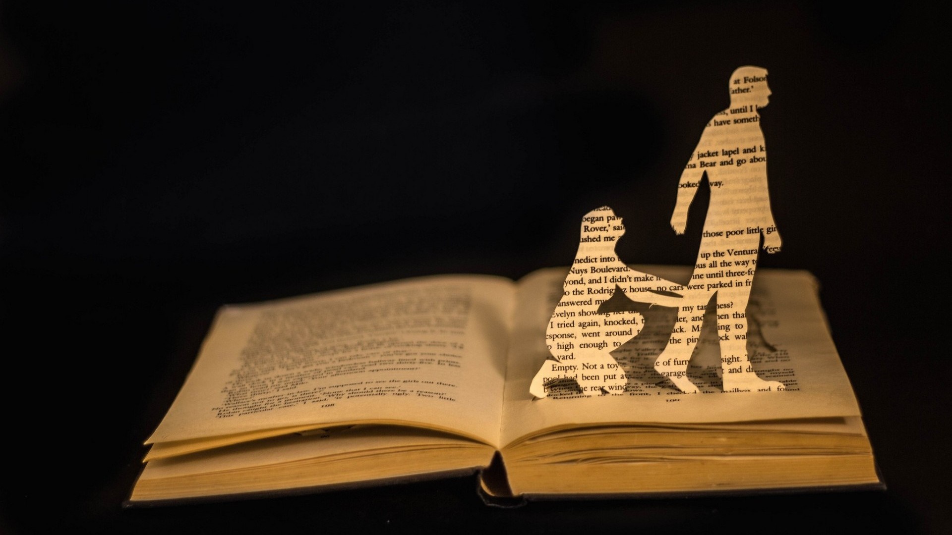 Paper cutouts of figures on an open book HD Wallpaper