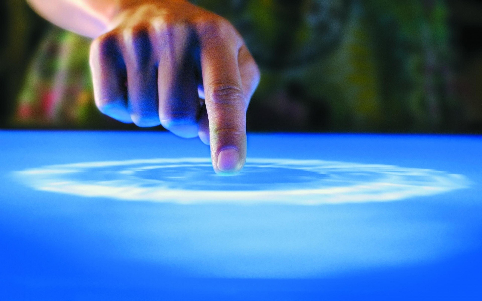 Finger touching a glowing blue surface creating ripples HD Wallpaper