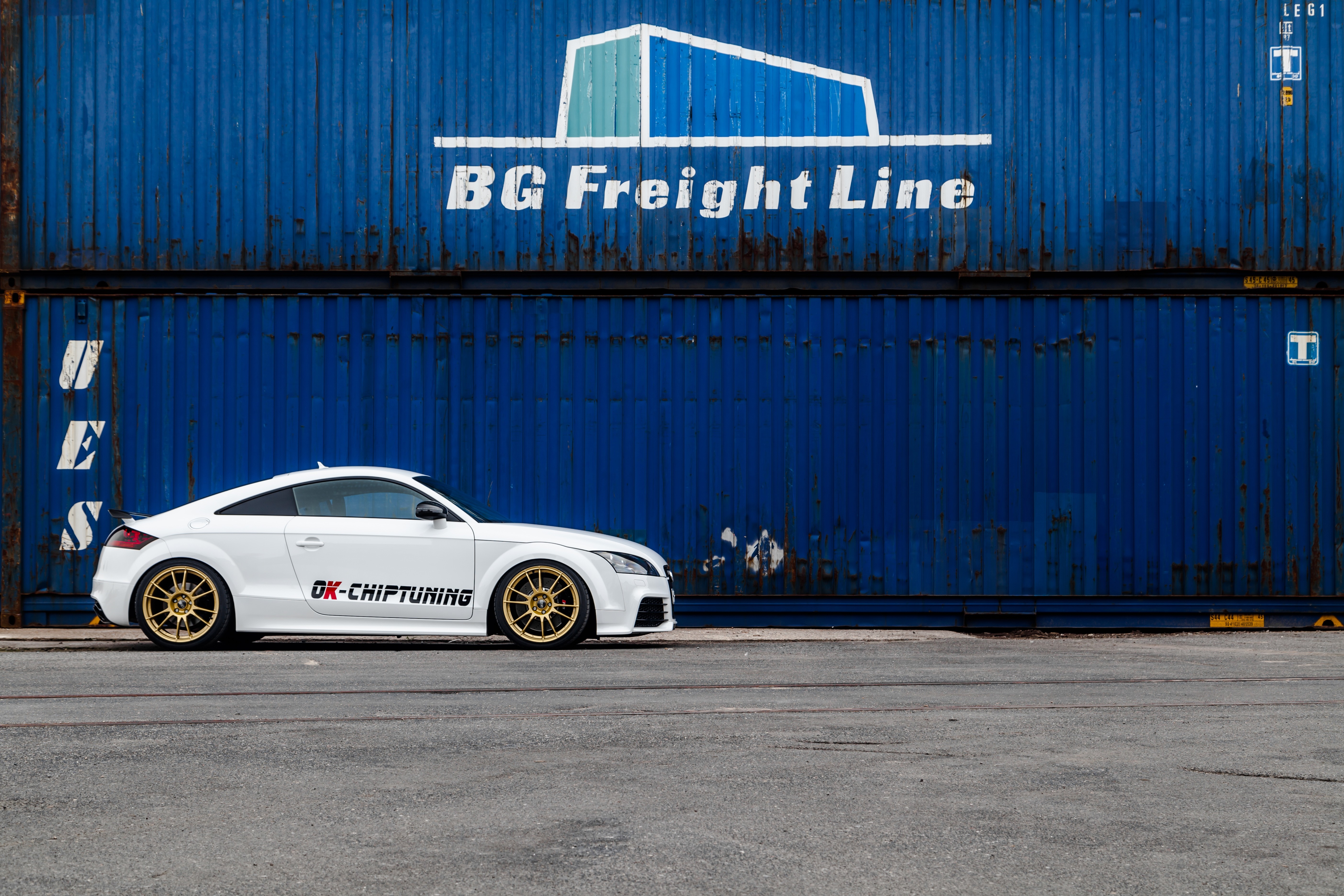White Audi TT with gold wheels parked by shipping containers HD Wallpaper