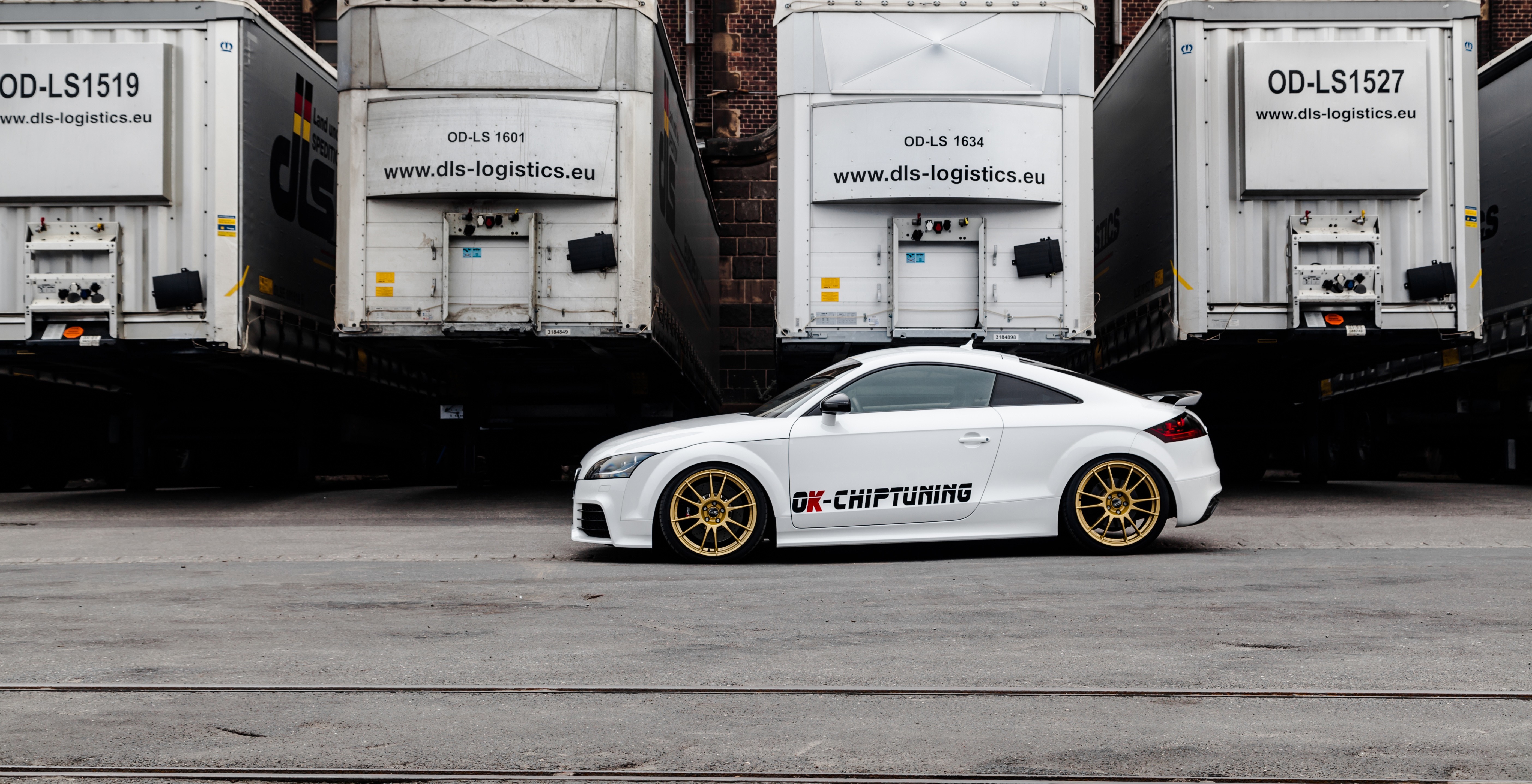 White Audi TT with OK-CHIPTUNING logo parked near trucks HD Wallpaper
