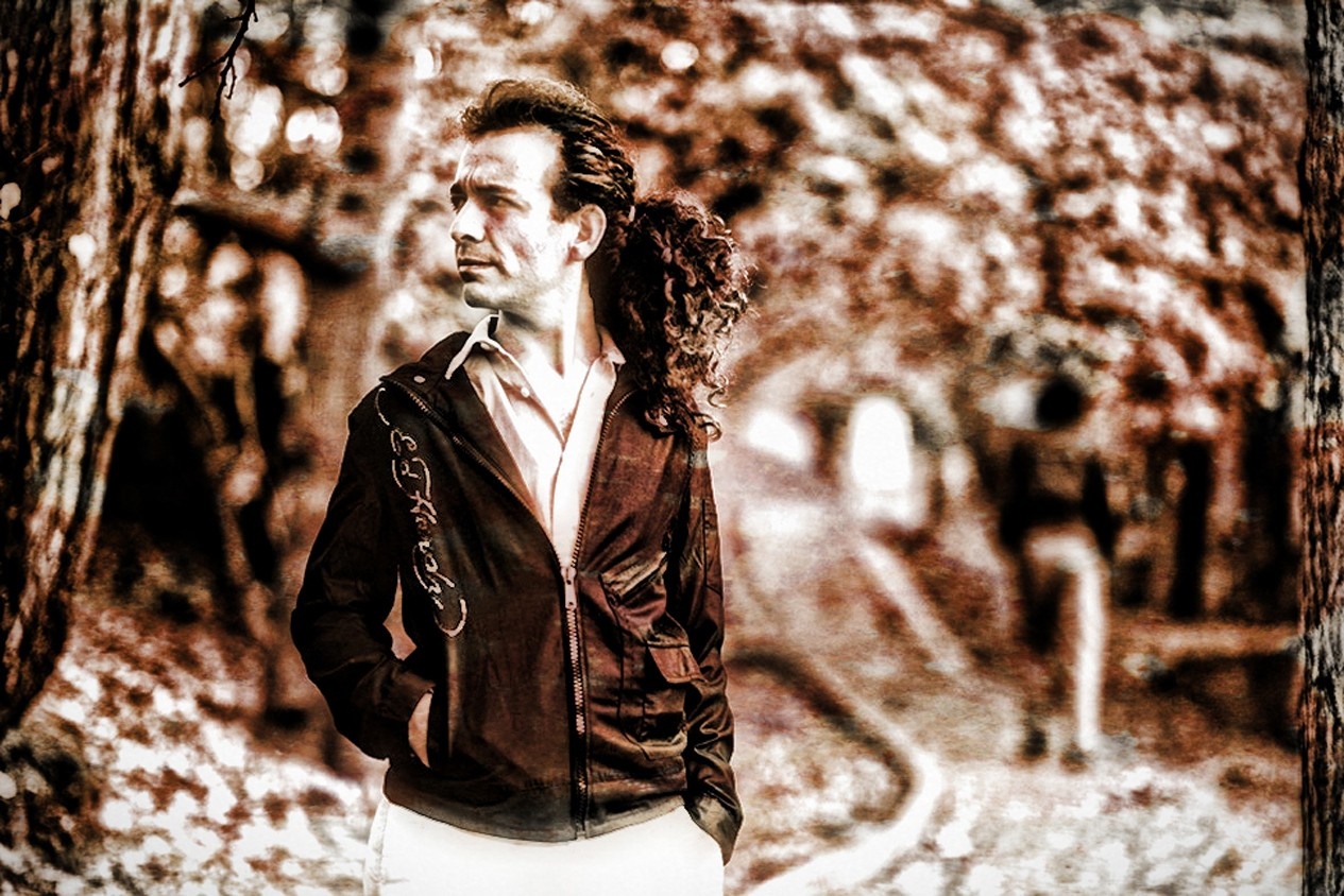 Man with curly hair in a jacket outdoors HD Wallpaper