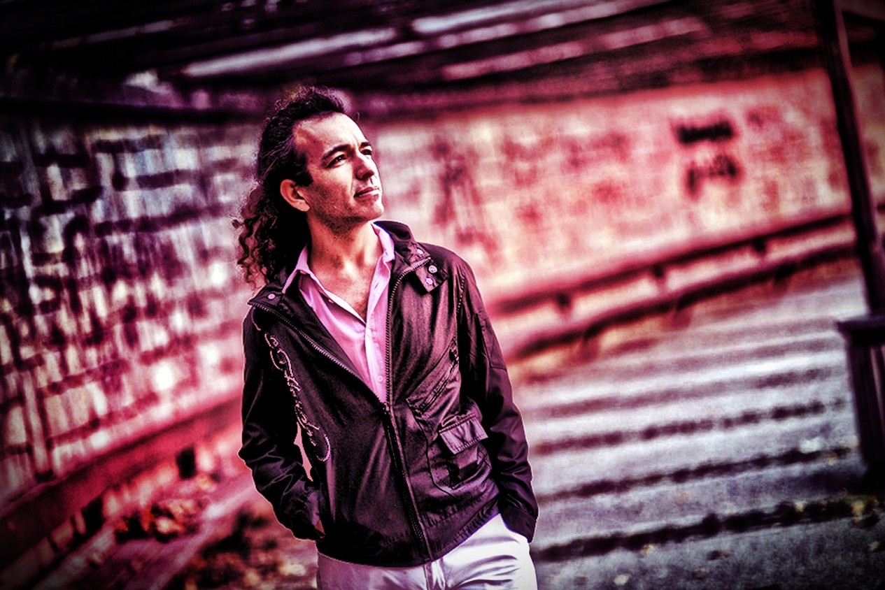 Man with curly hair wearing a pink shirt and black jacket HD Wallpaper