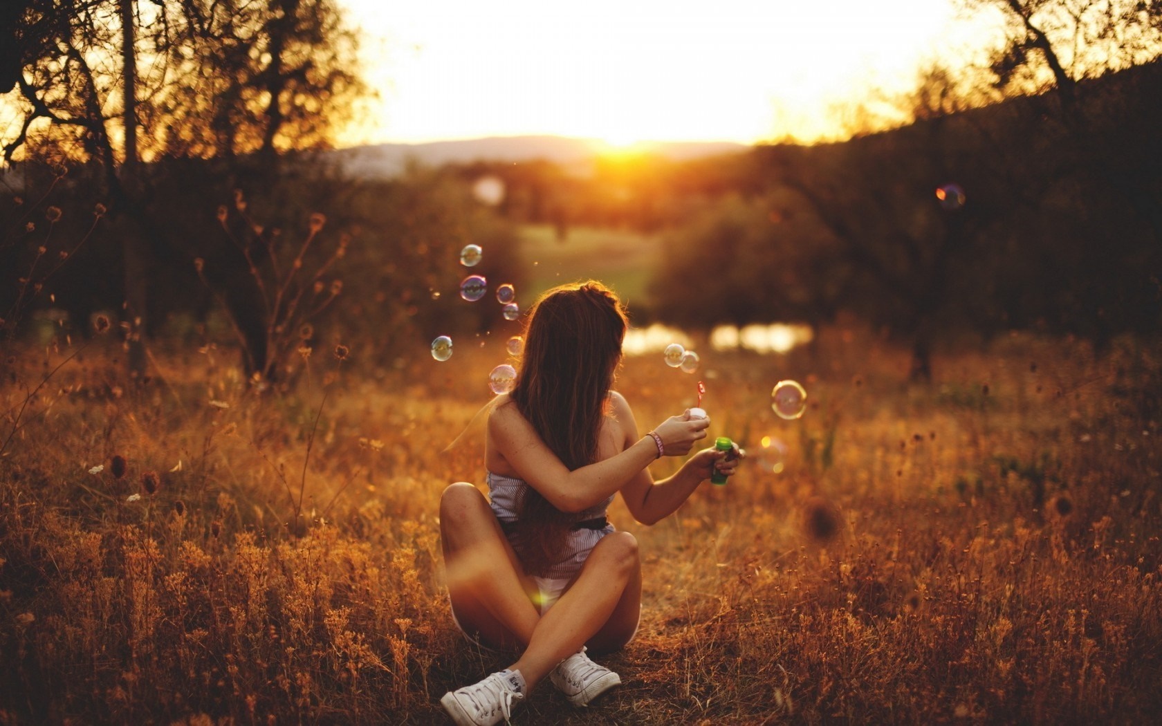 Woman blowing bubbles at sunset in a field HD Wallpaper