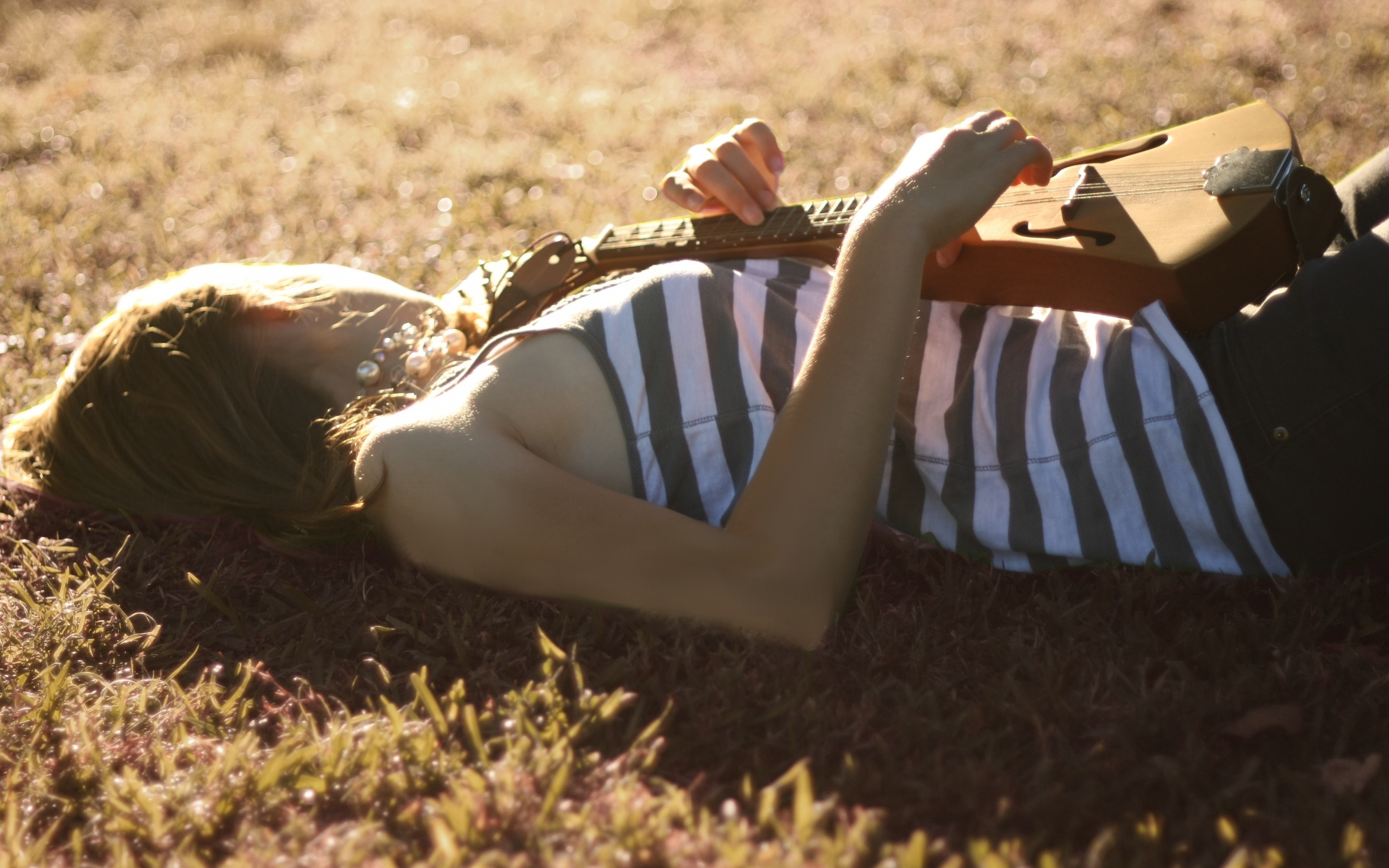 Woman lying on grass playing a musical instrument HD Wallpaper