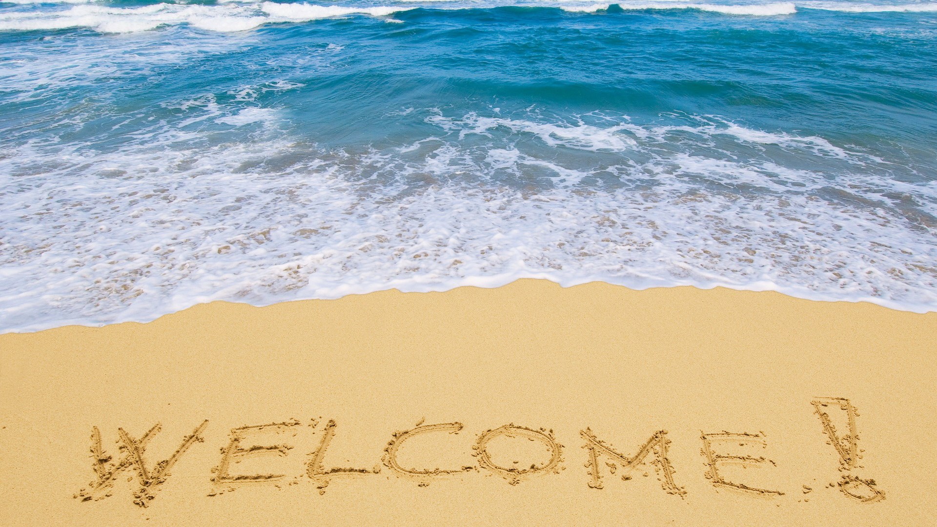 Welcome written in sand on a beach with waves HD Wallpaper