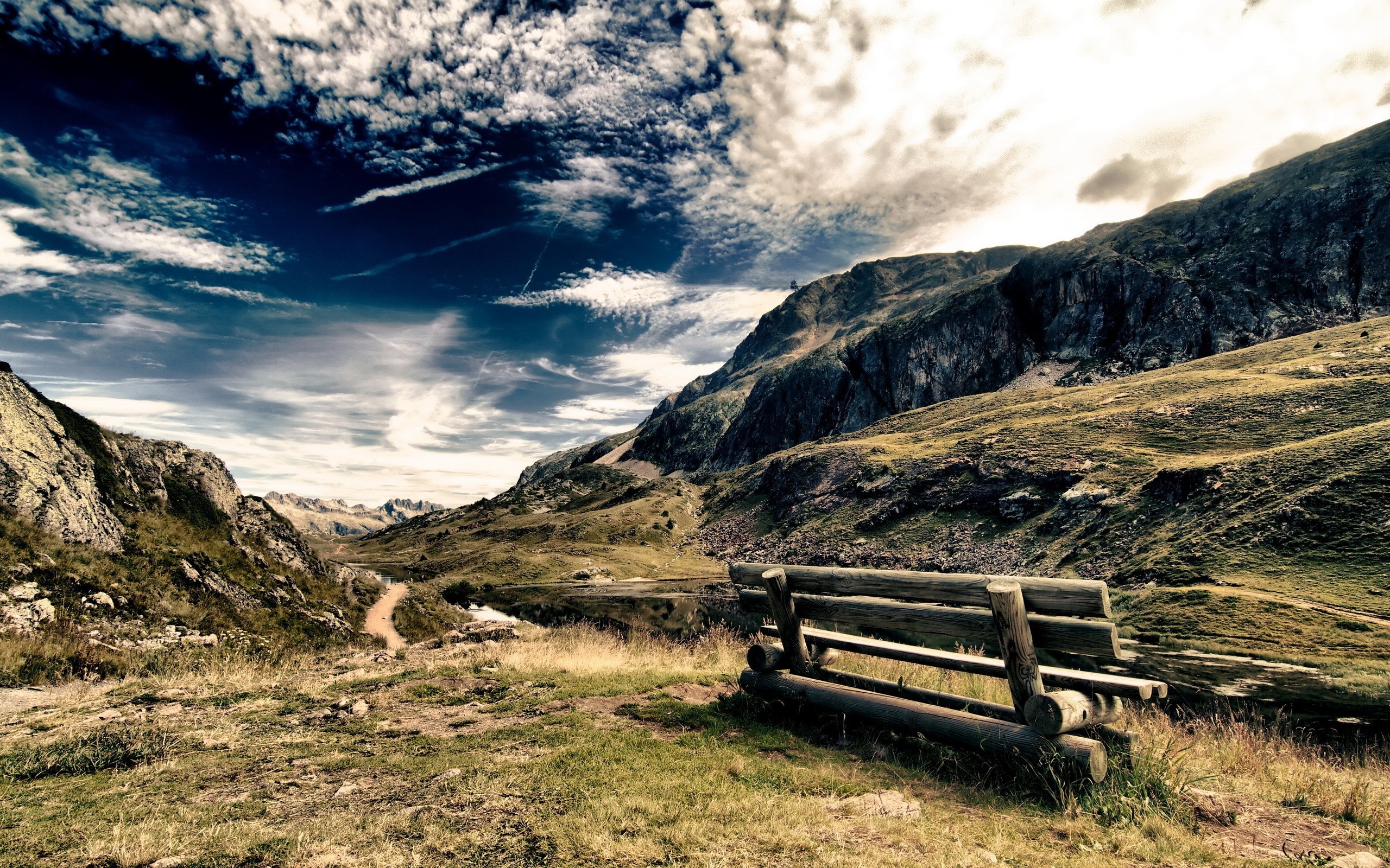 Wooden bench overlooking a mountain valley with a lake HD Wallpaper