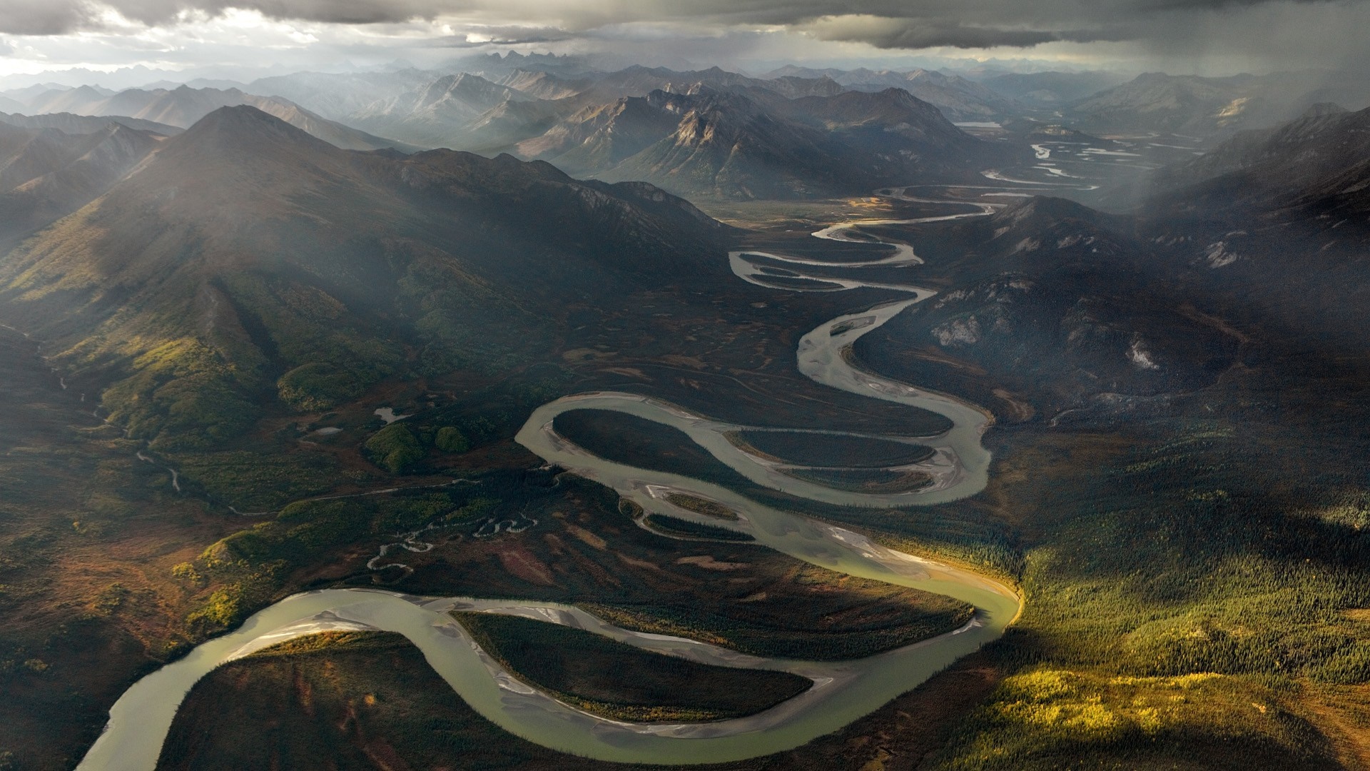 Aerial view of a winding river through mountains HD Wallpaper