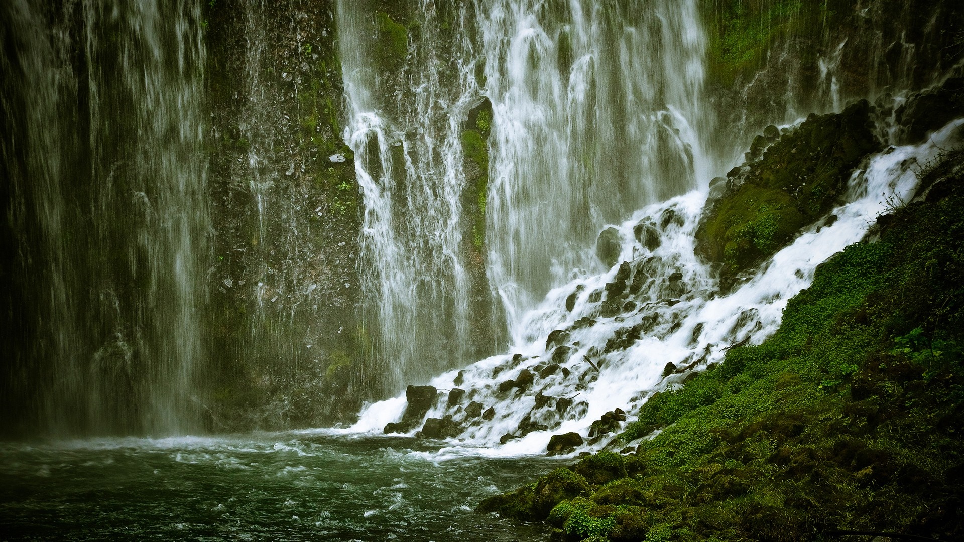 Waterfall cascading over mossy rocks into a dark pool HD Wallpaper