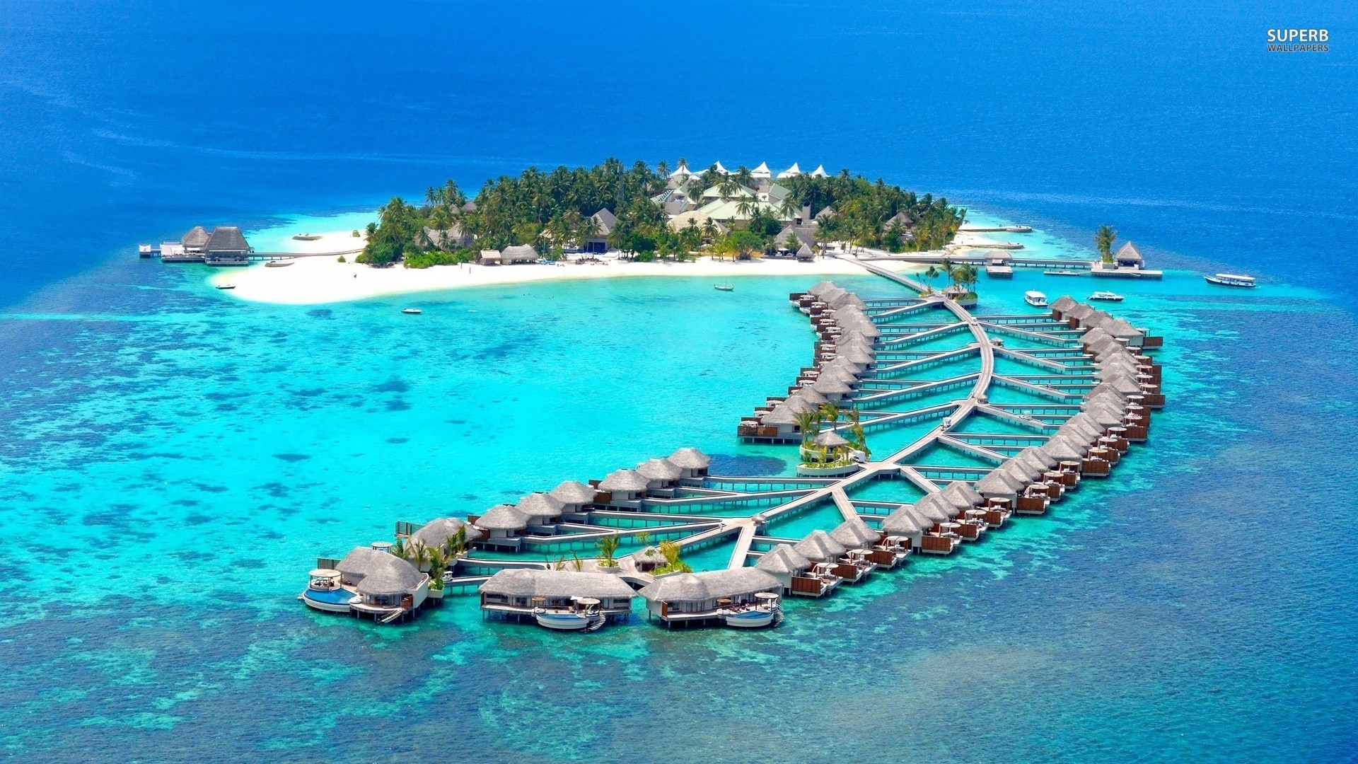 Aerial view of overwater bungalows and a tropical island resort HD Wallpaper