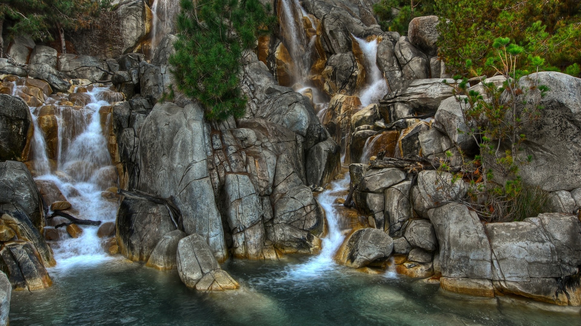 Waterfall cascading over rocks into a pool HD Wallpaper