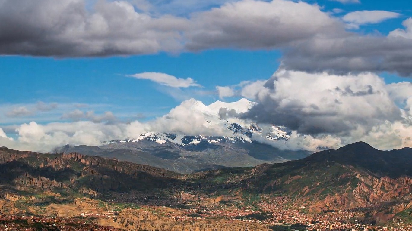 Snow-capped mountains above a valley city HD Wallpaper