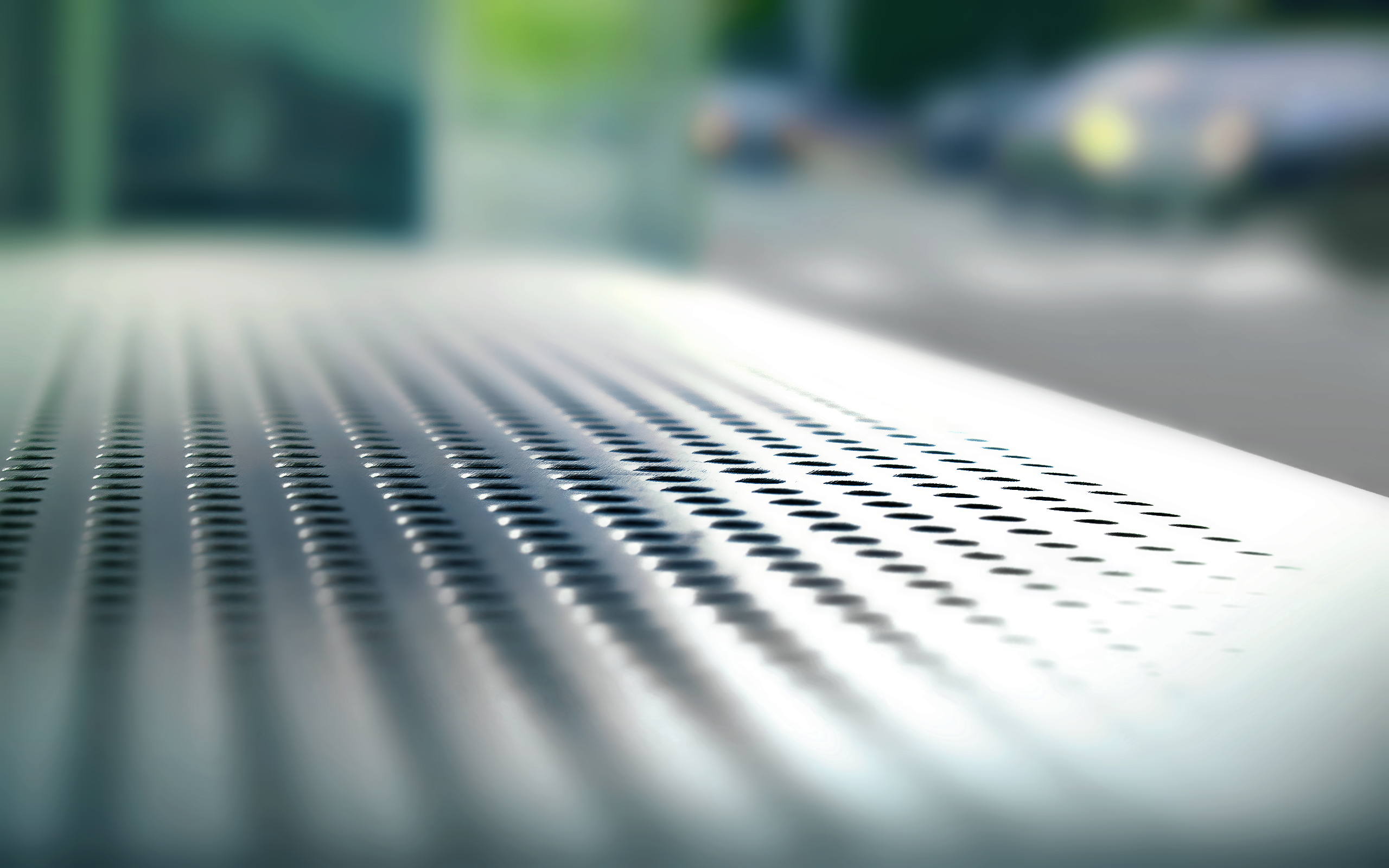 Close-up of perforated metal surface with blurred background HD Wallpaper