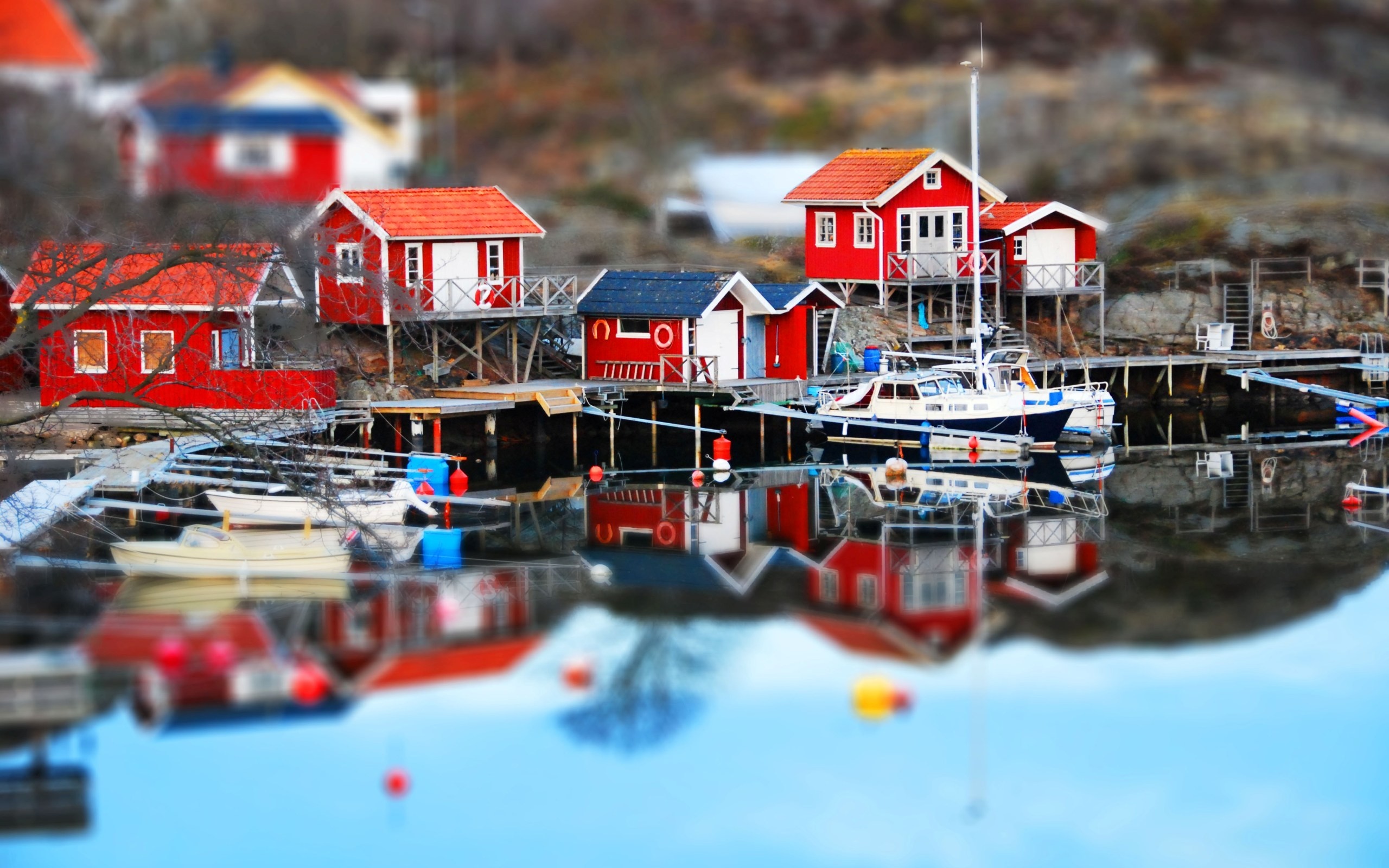 Red houses and boats on a lake with reflections HD Wallpaper