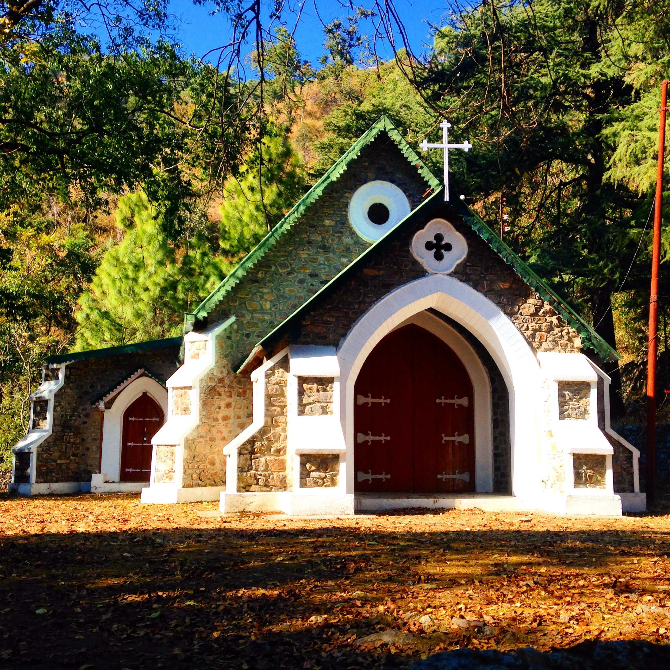 Stone church with red doors in a forest HD Wallpaper