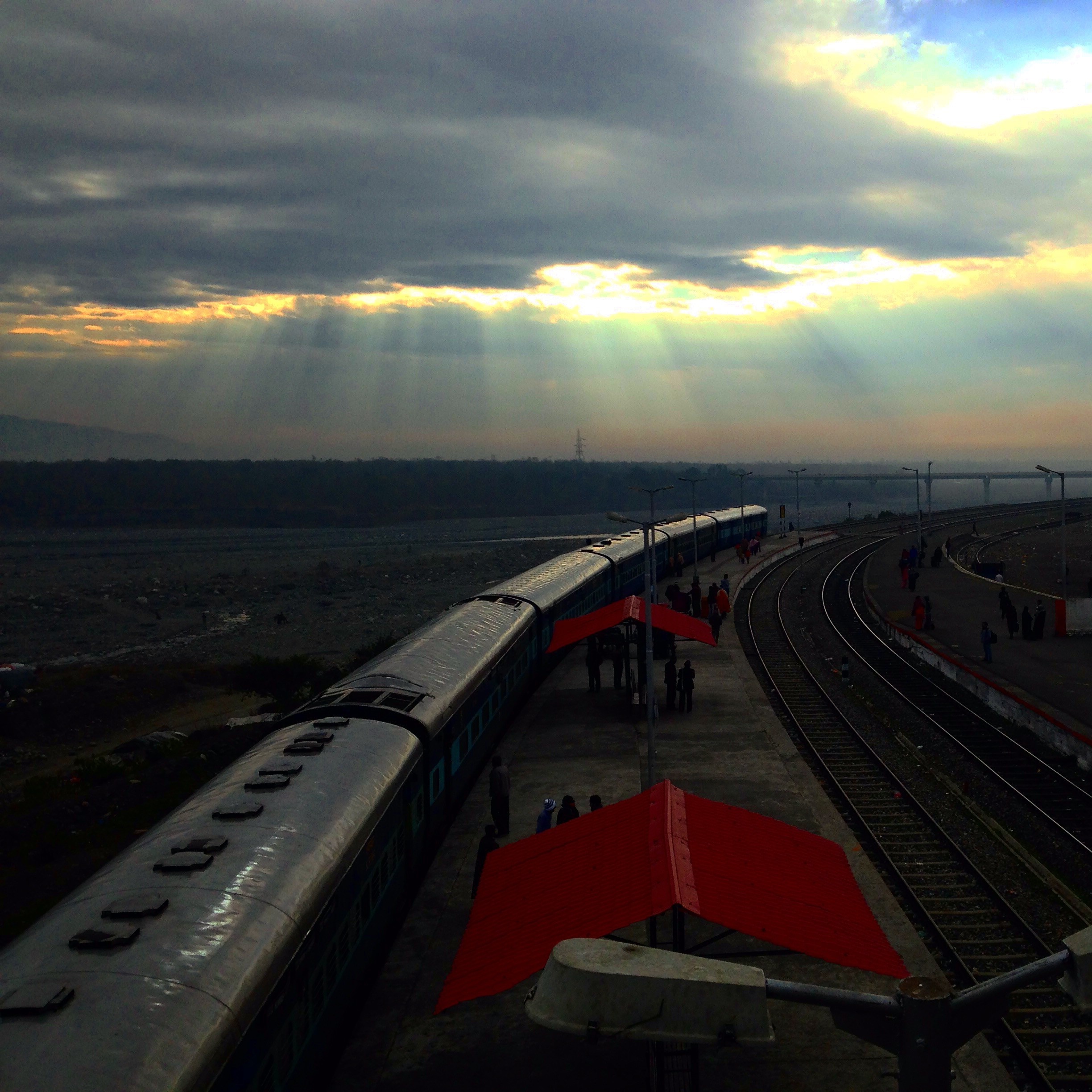 Train at a station with sunbeams through clouds HD Wallpaper