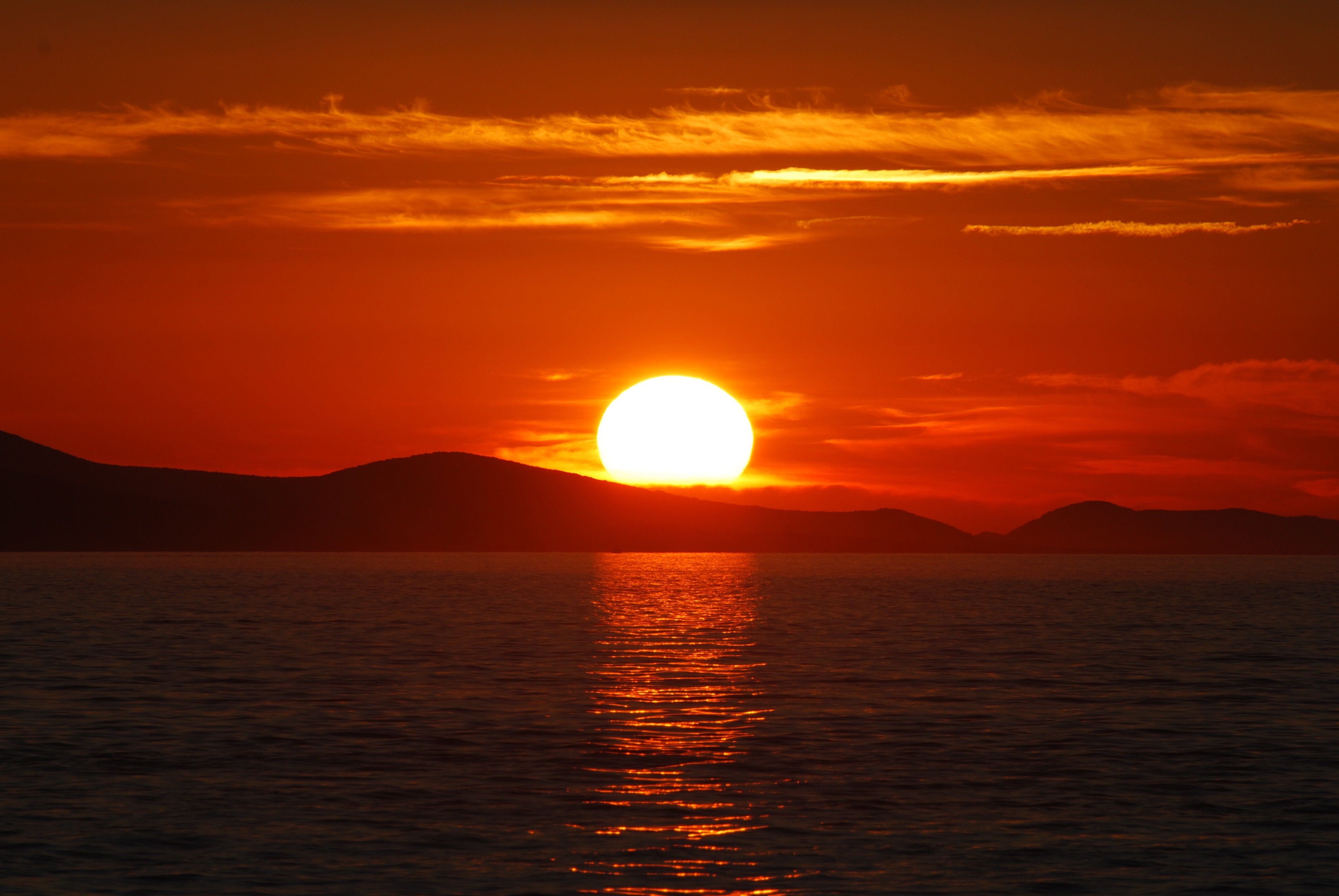 Sunset over the sea with mountains on the horizon HD Wallpaper