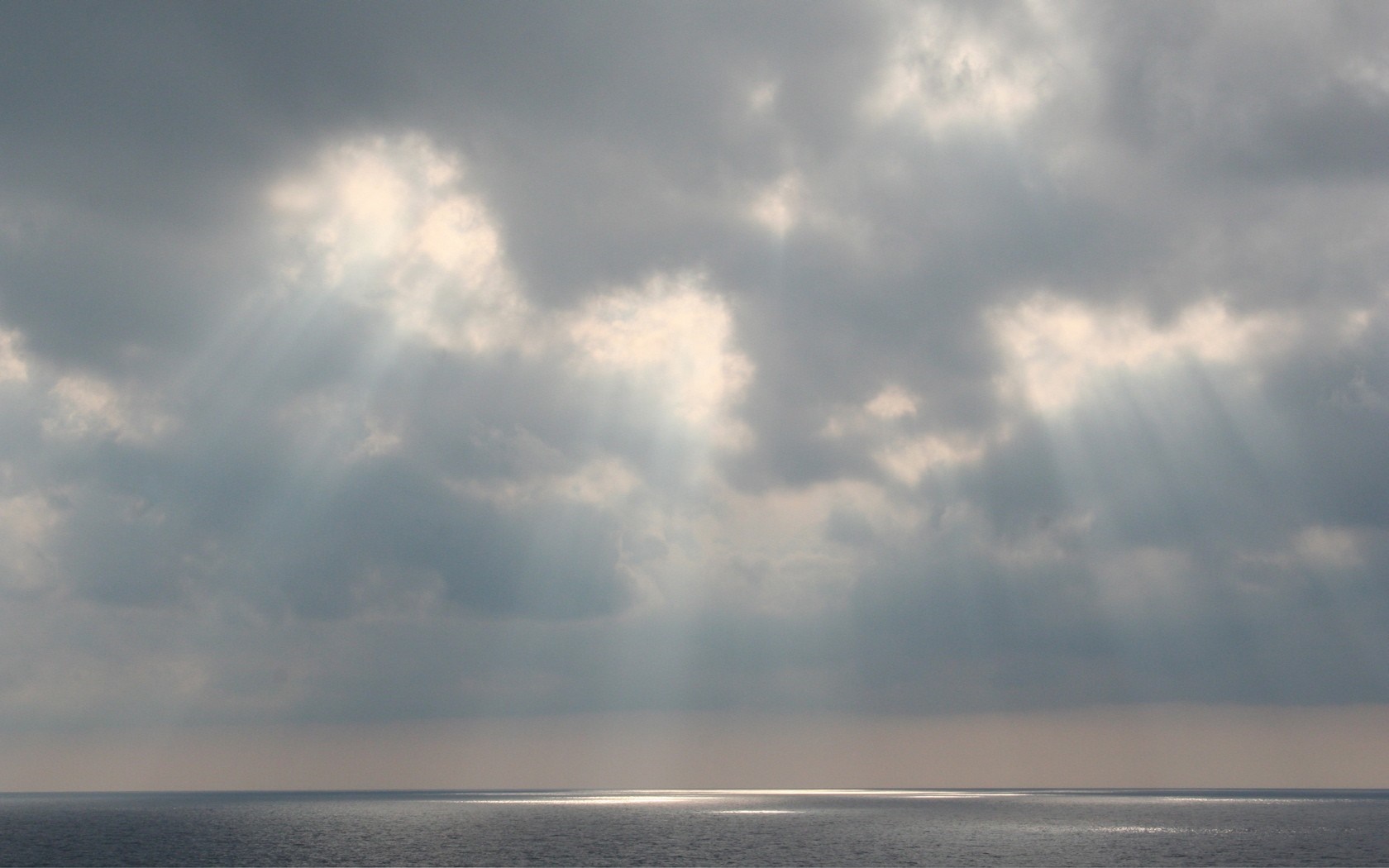 Sunlight breaking through clouds over the ocean horizon HD Wallpaper