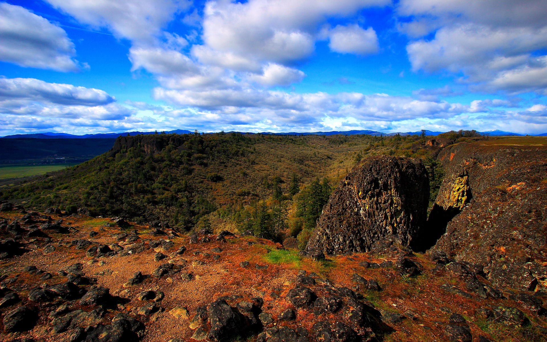 Rocky cliff overlooking a valley under a cloudy sky HD Wallpaper