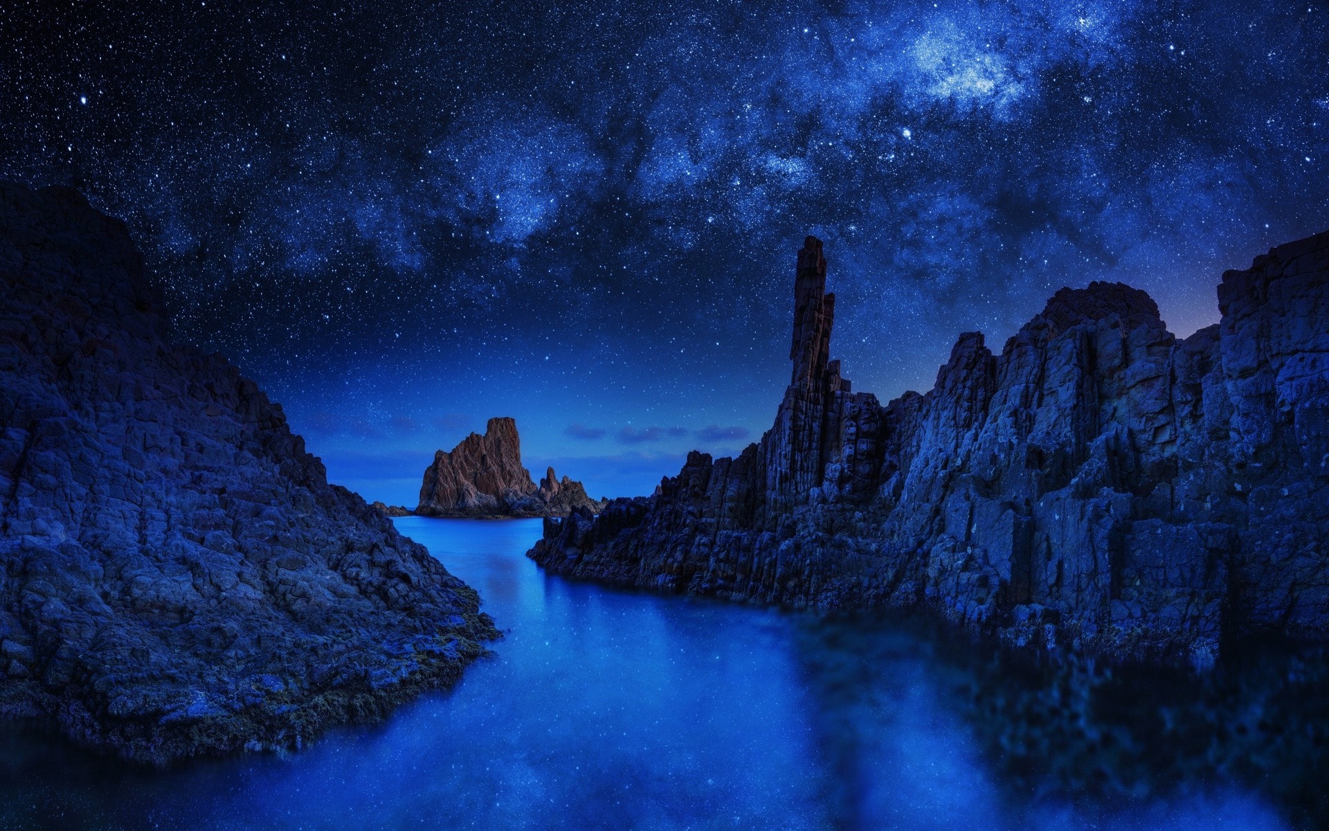 Rocky coast under a starry night sky HD Wallpaper