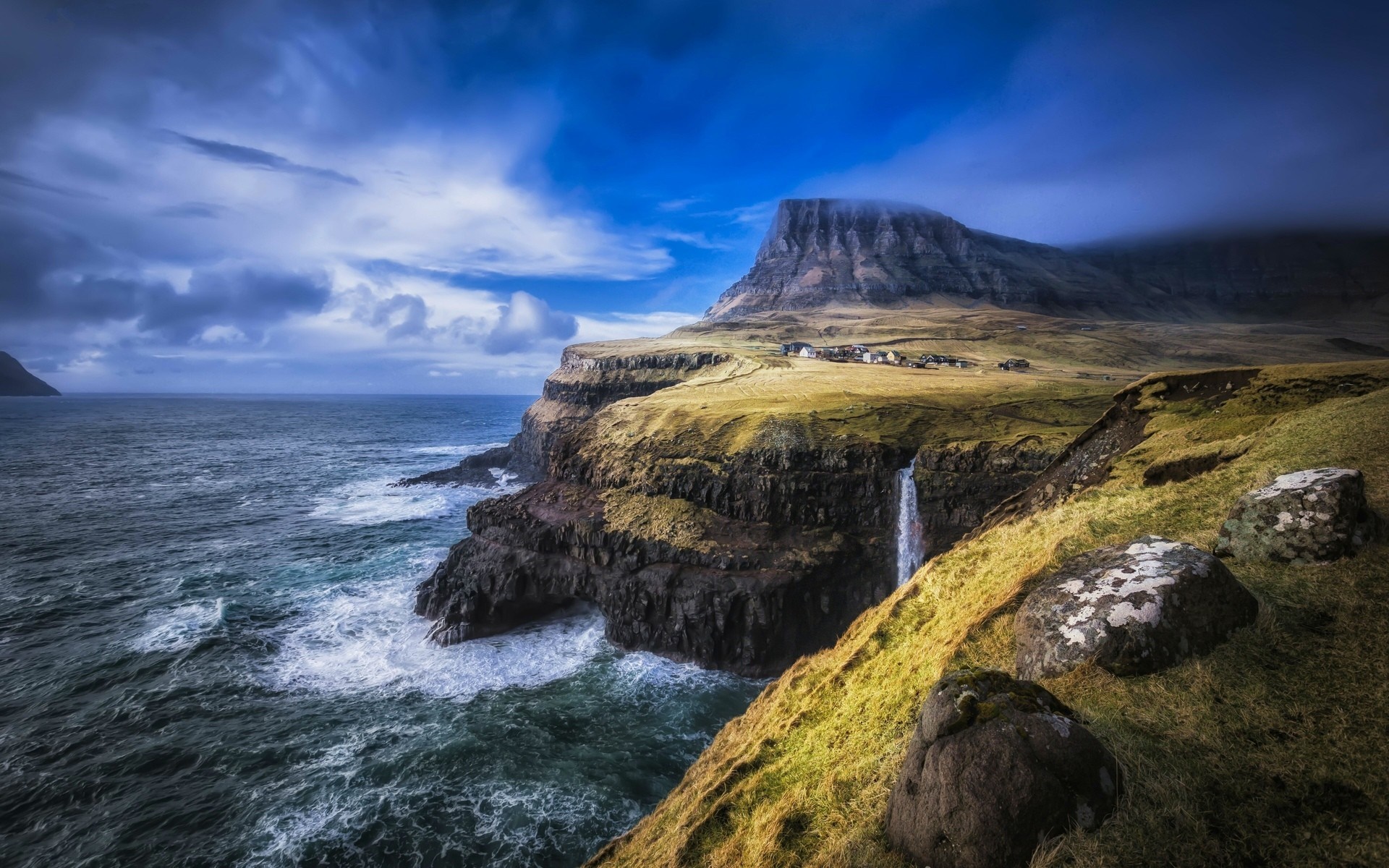 Waterfall cascading from cliffs into the sea at Faroe Islands HD Wallpaper