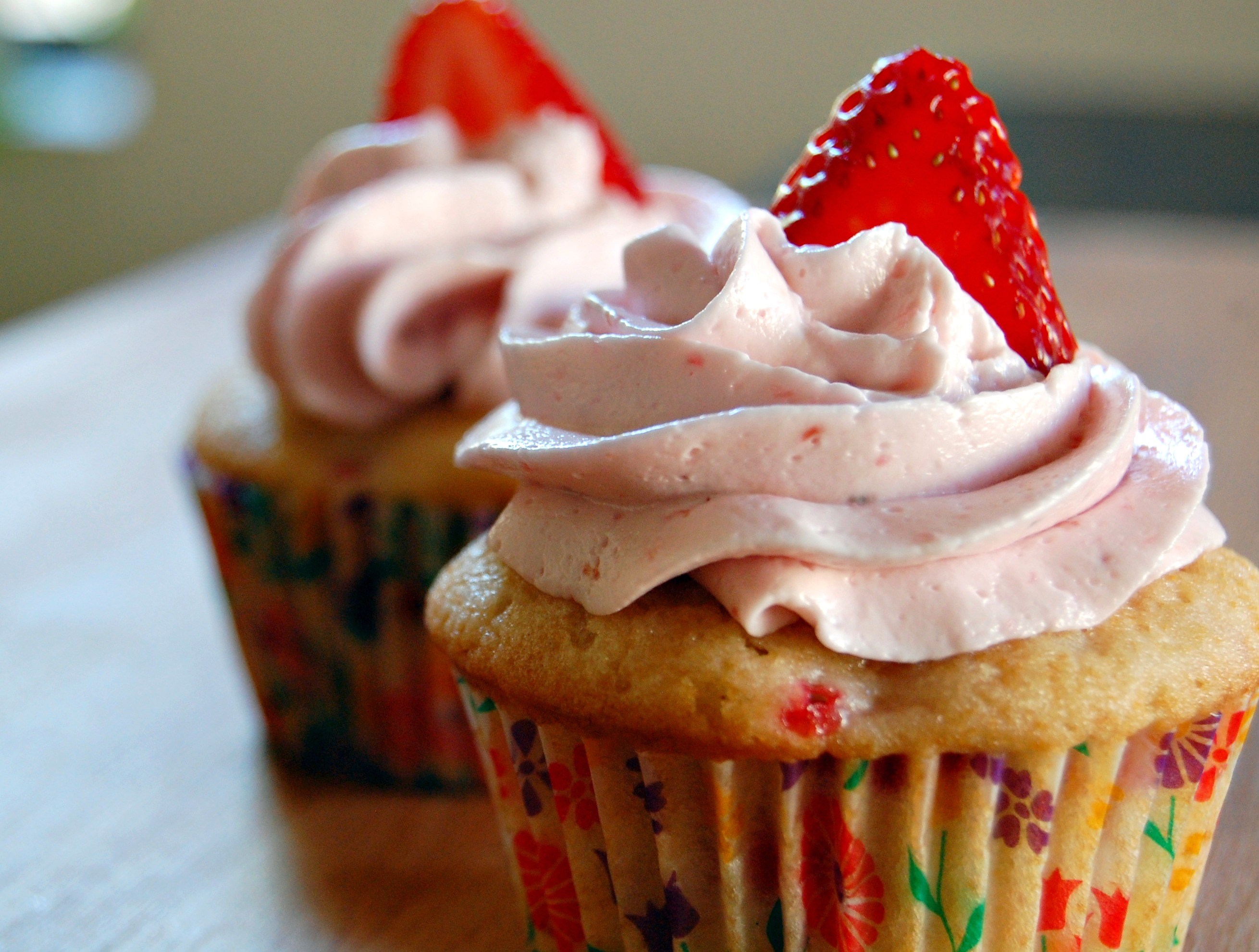 Two strawberry cupcakes with pink frosting HD Wallpaper