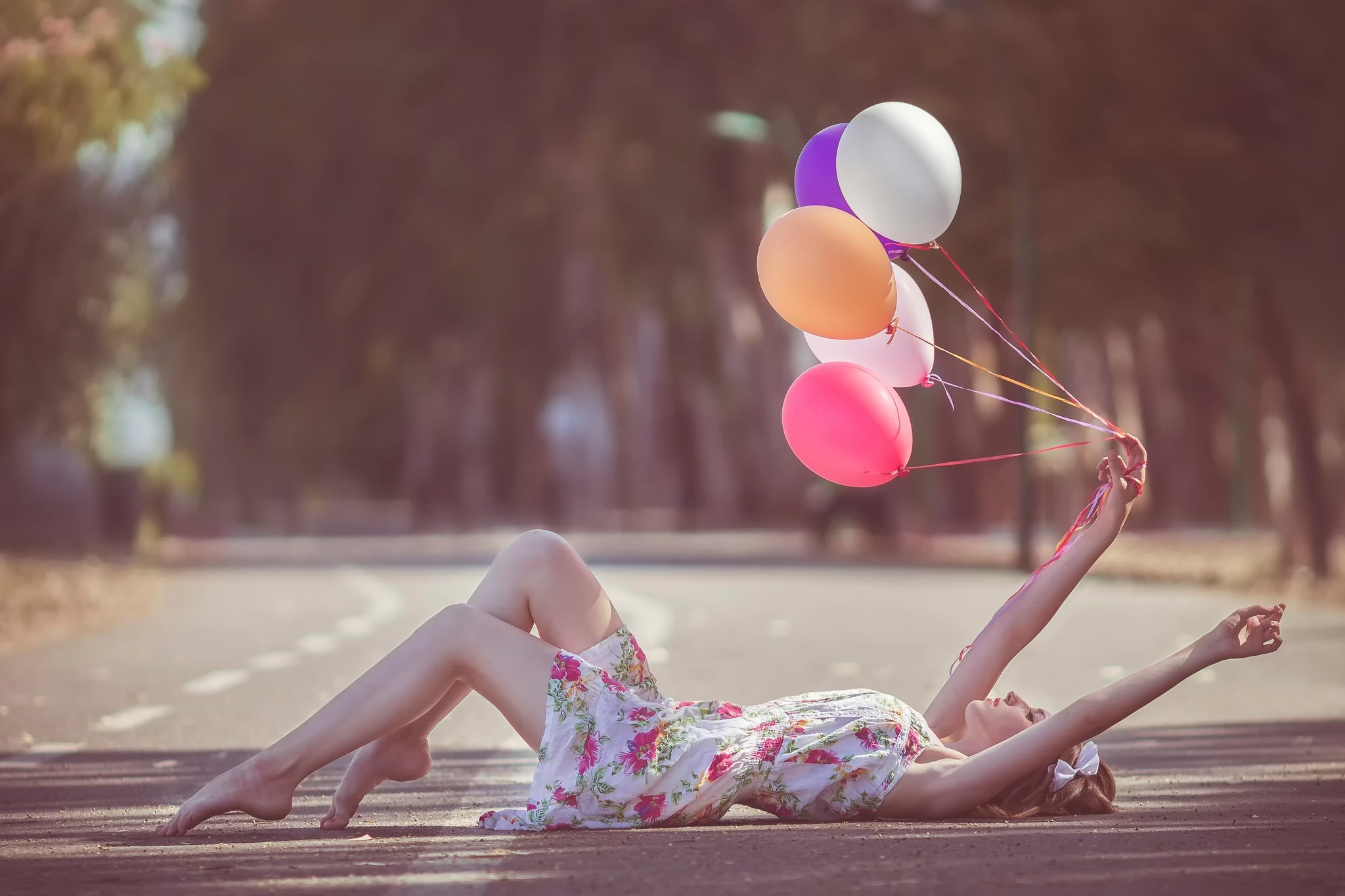 Woman lying on the ground holding balloons HD Wallpaper