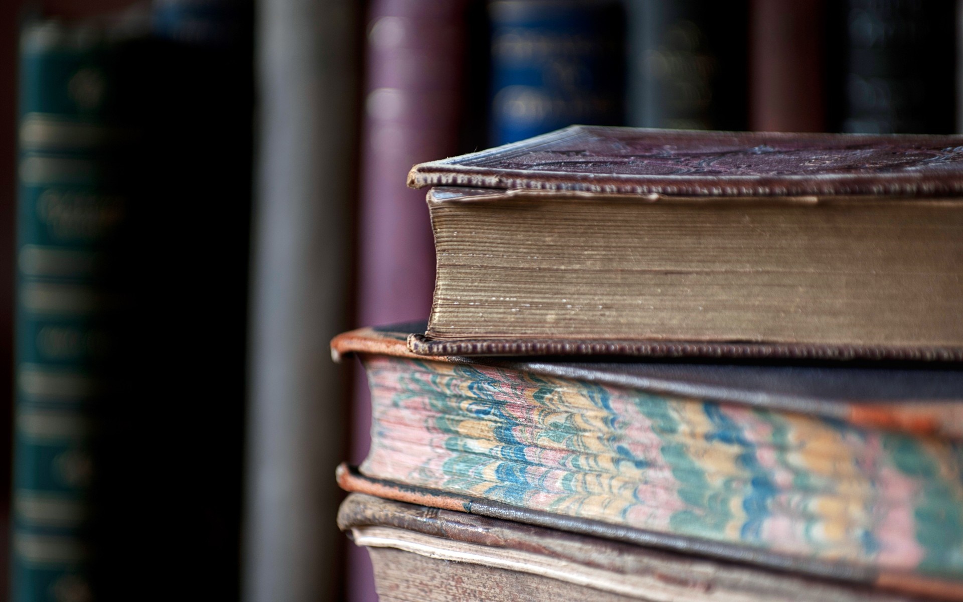 Stack of old books with marbled pages HD Wallpaper
