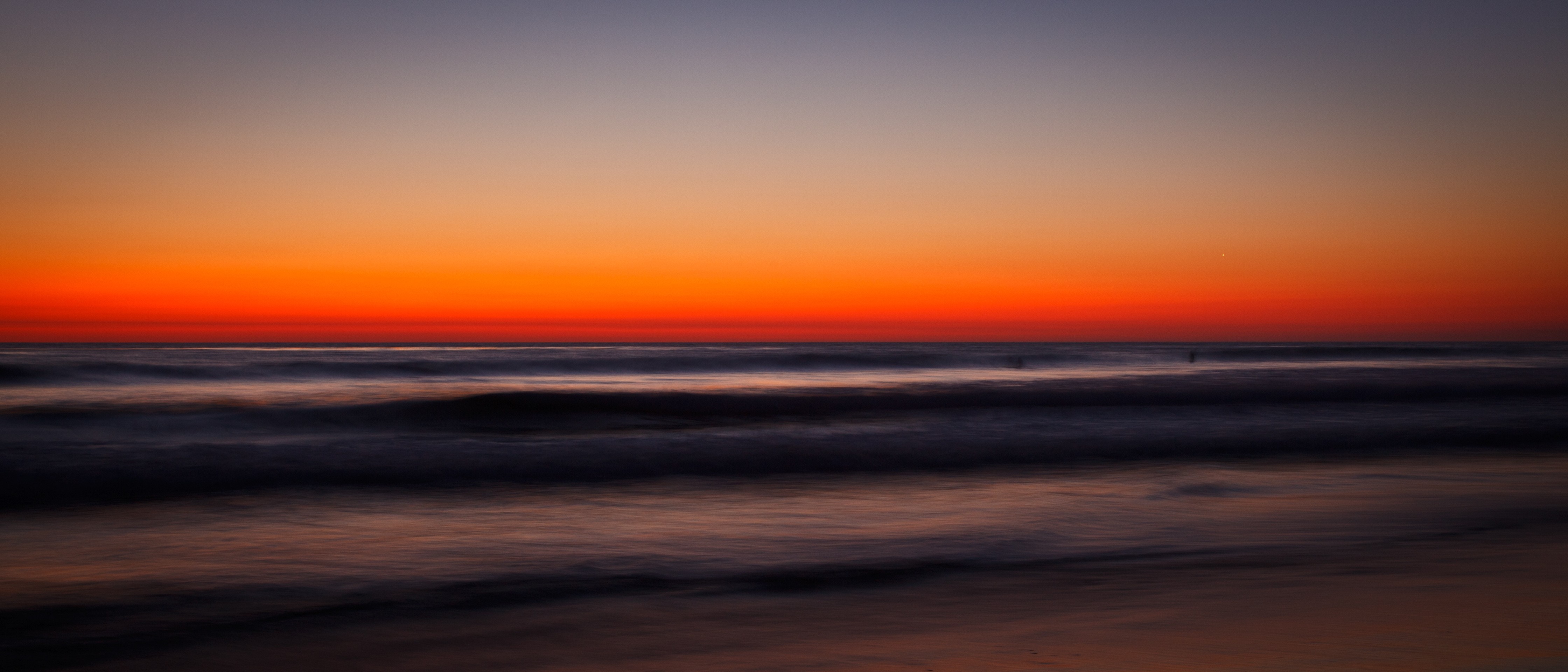 Ocean waves at sunset with vibrant orange sky HD Wallpaper