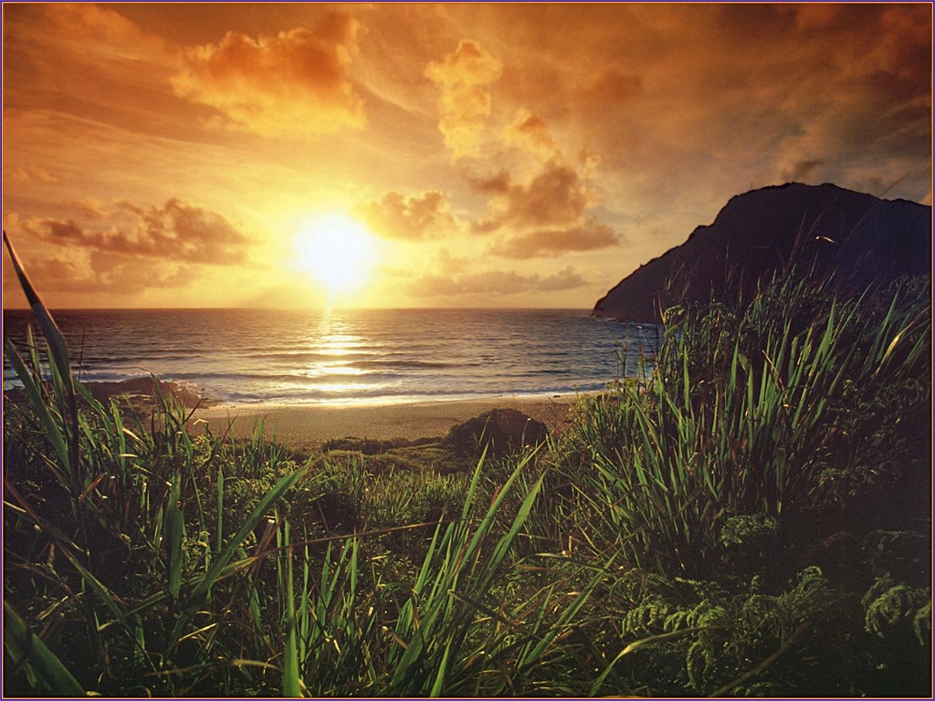Sunset over the ocean with a mountain and grass HD Wallpaper
